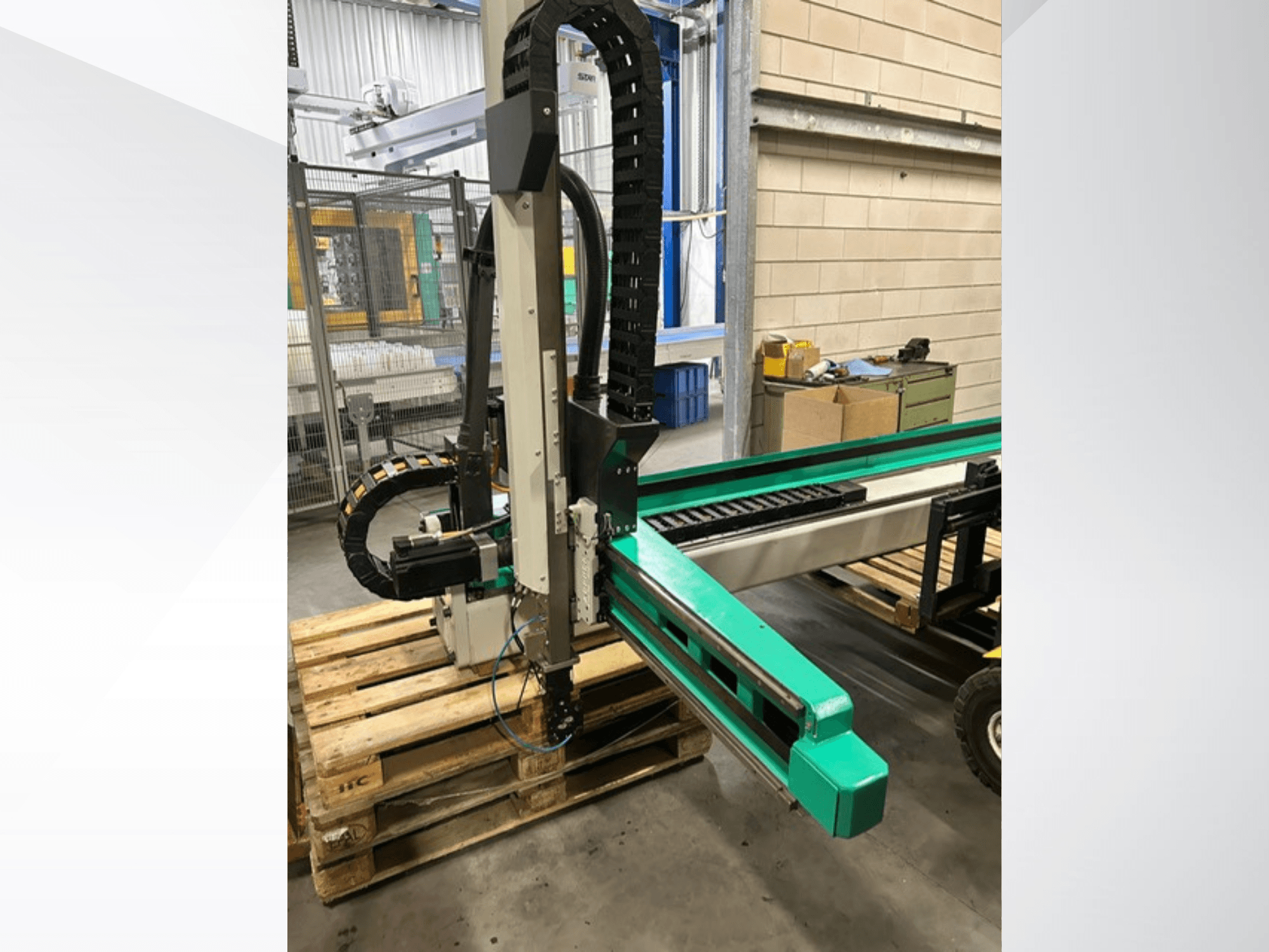Arburg Multilift Select 15kg quer, sivukuva työkappaleen käsittelyjärjestelmästä puulavoilla, jossa näkyy robottivarsi ja ohjauskomponentit.