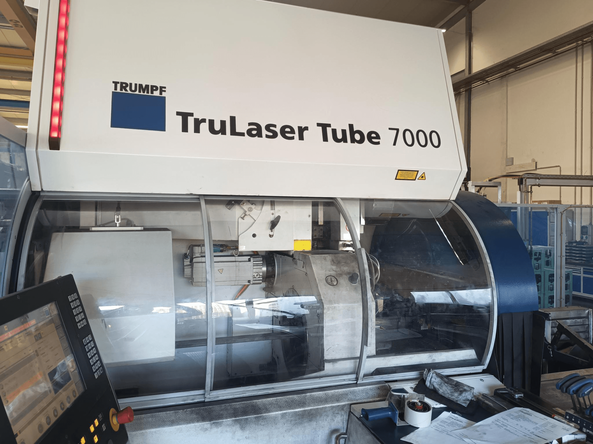 TRUMPF TruLaser Tube 7000, etukuva koneesta ja ohjauspaneelista, jossa esitellään laserleikkausominaisuuksia ja työtilaa.