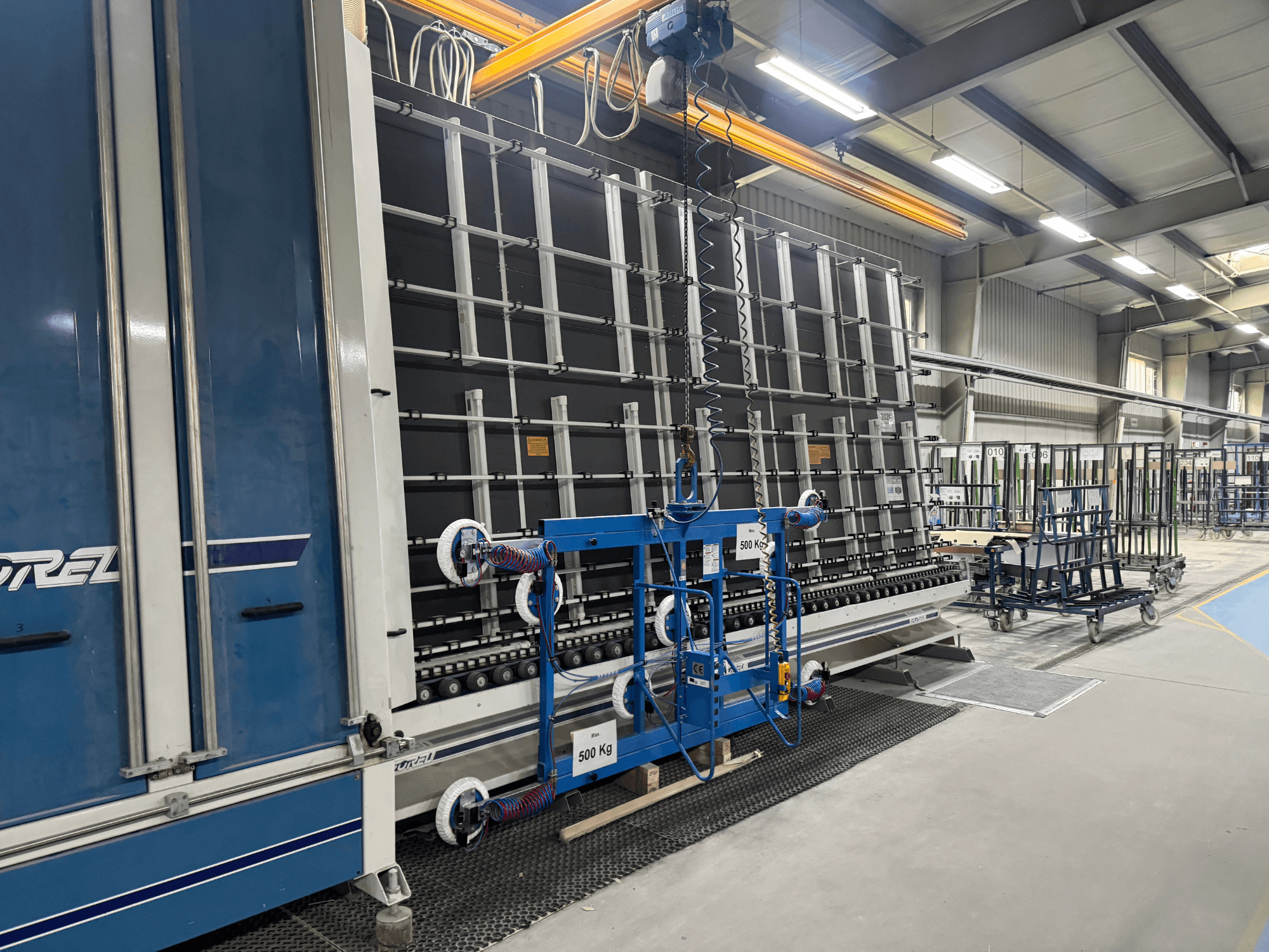 Drelin teollisuuslaitteet, joissa on suuri runko ja nostomekanismi, kuvattuna sivukuvasta tehdasympäristössä.