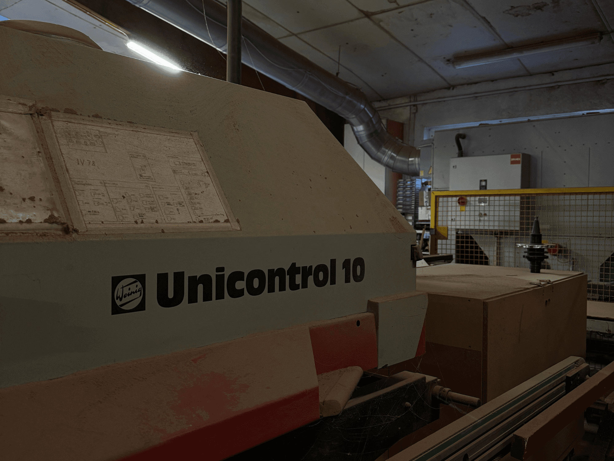 Weinig Unicontrol 10 -kone sivukulmasta katsottuna, pölyinen pinta, etupaneelissa näkyvät tekniset kaaviot.