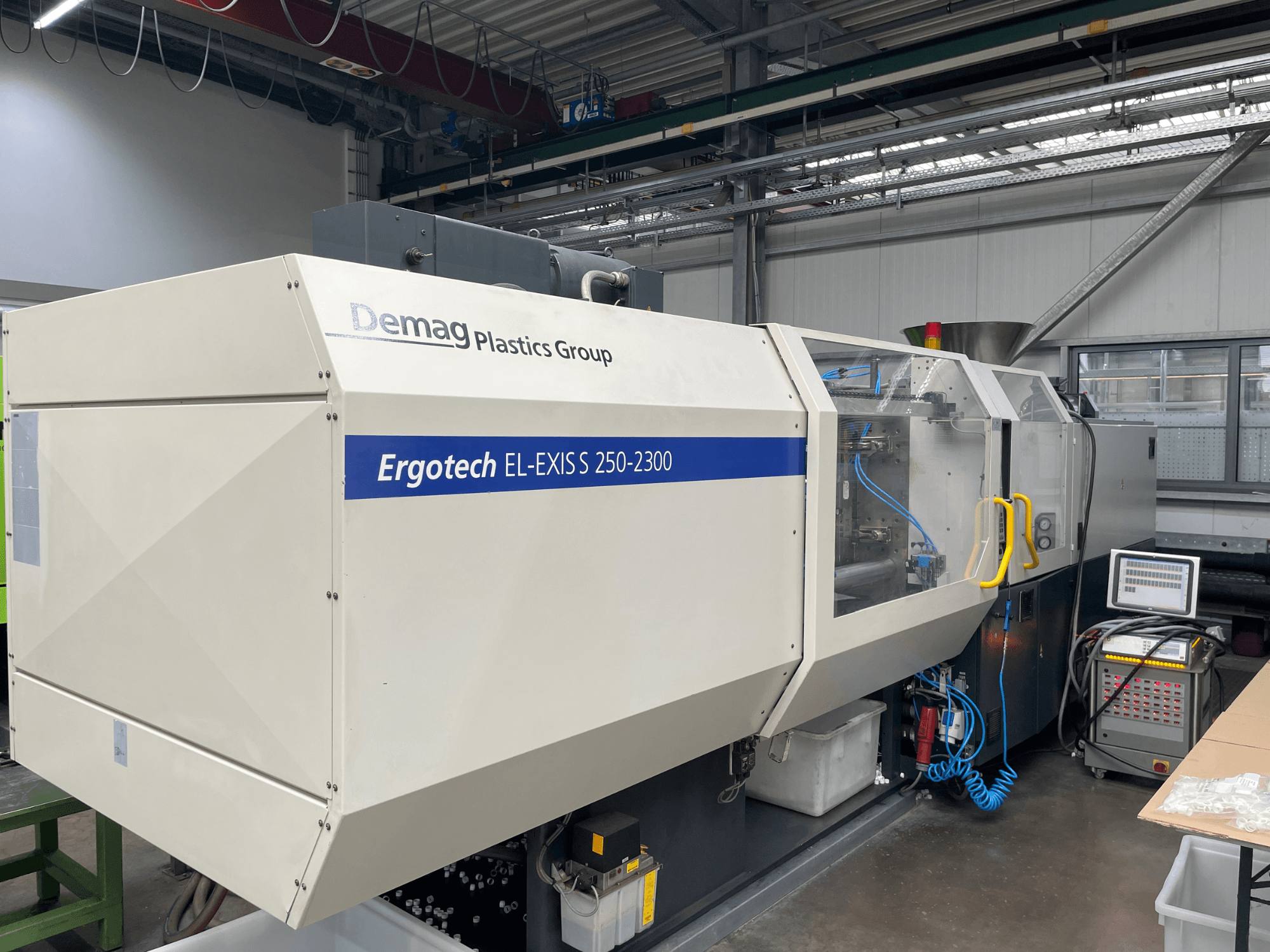 Demag Ergotech EL-EXIS S 250-2300 -ruiskuvalukone, sivukuva, jossa näkyy ohjauspaneeli ja syöttöjärjestelmä.