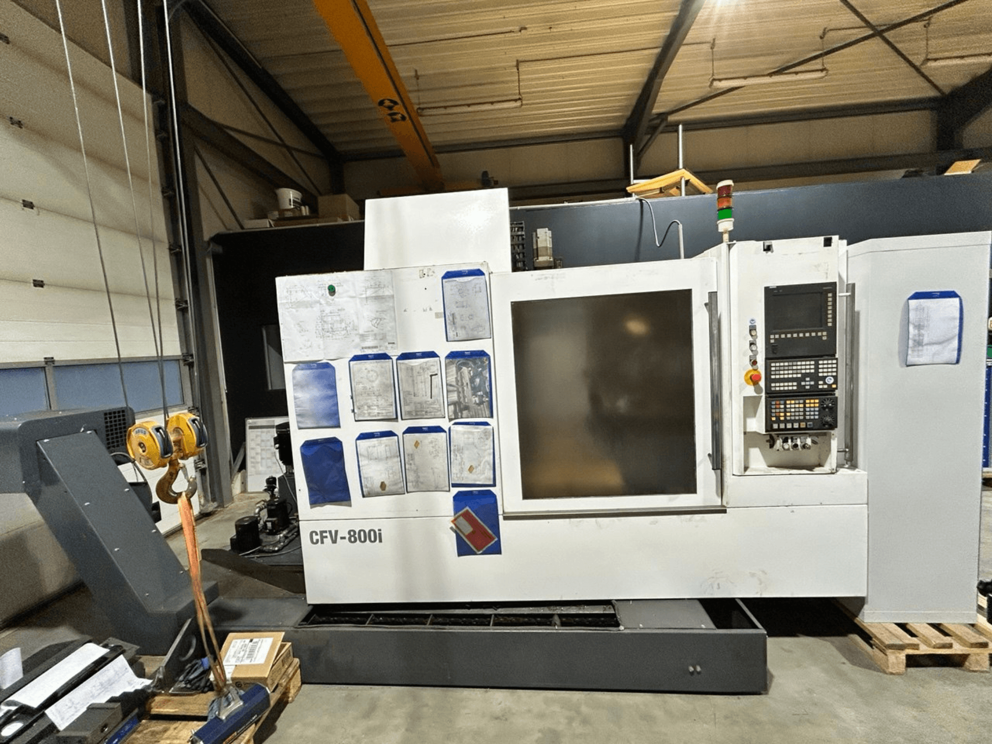 CFV-800i CNC-kone etukuvassa, jossa on ohjauspaneeli, asiakirjat sivulla ja siltanosturi tehdasasetuksissa.