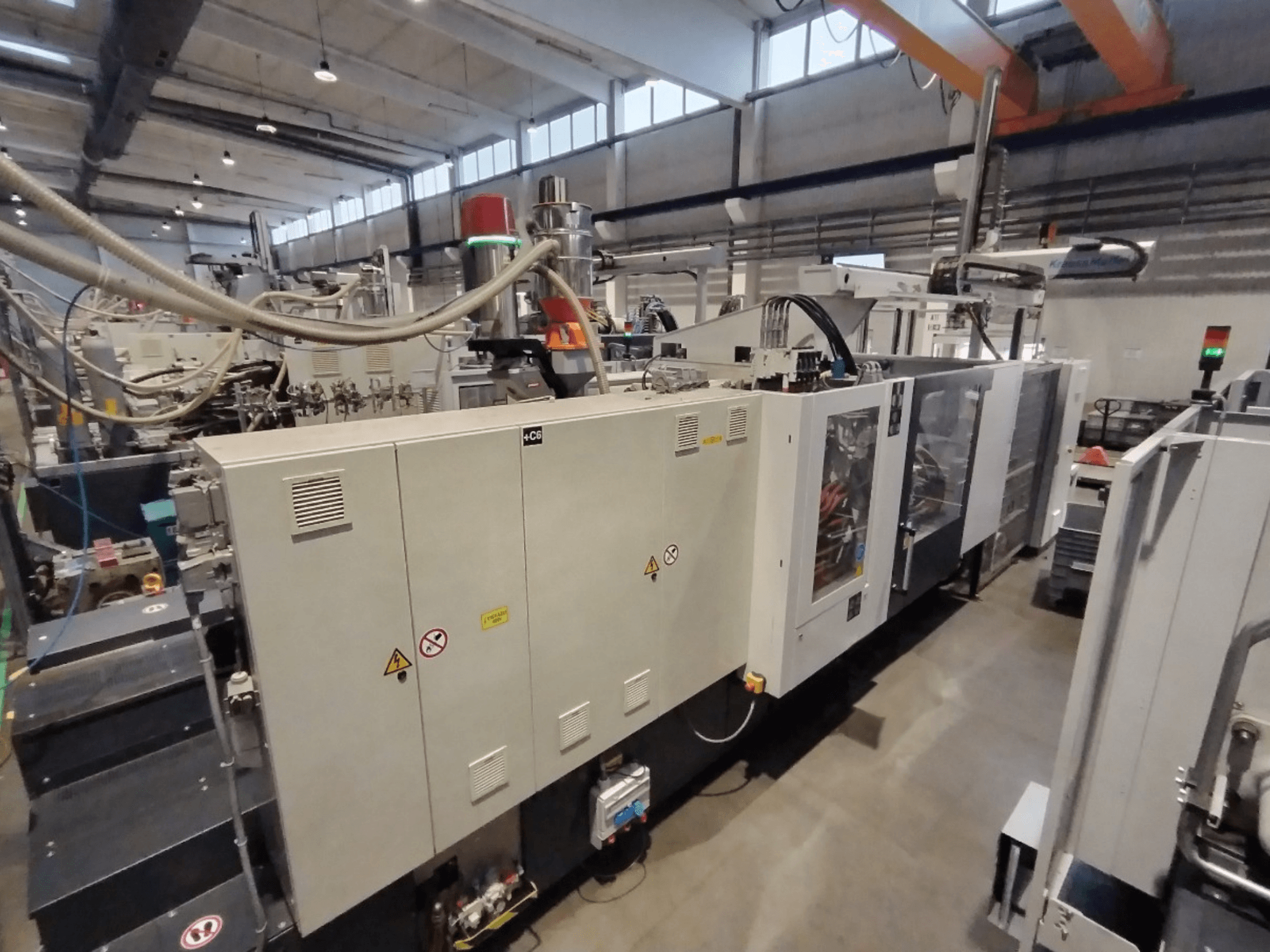 Teollinen ruiskuvalukone sivukuvassa, jossa on ohjauspaneeli ja turvallisuusvaroitukset. Tuotemerkki: Tuntematon.