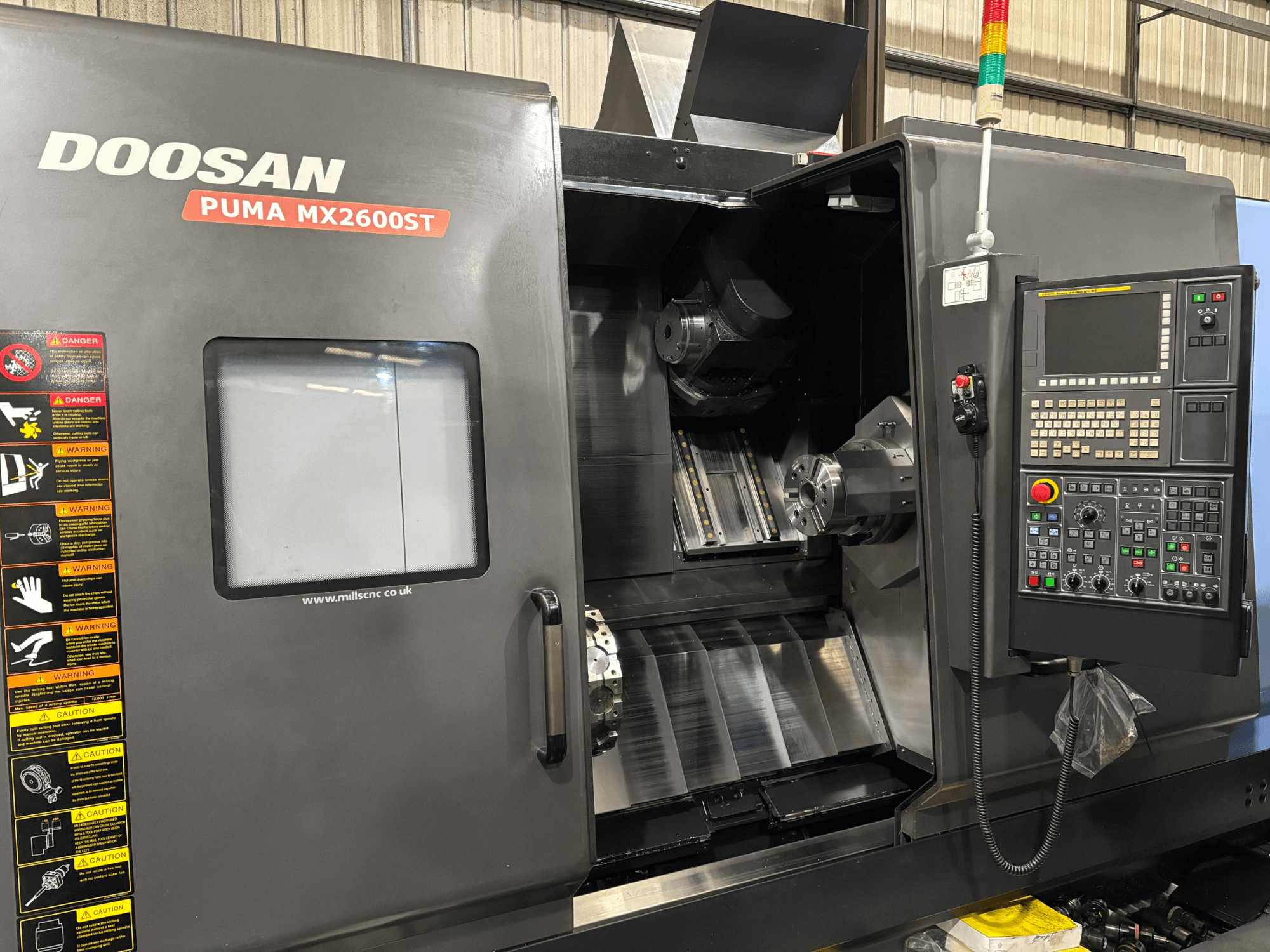 Doosan PUMA MX2600ST CNC-sorvi, etukuva, jossa näkyy ohjauspaneeli, kara ja työstöalue, jossa on näkyviä turvallisuusvaroituksia.