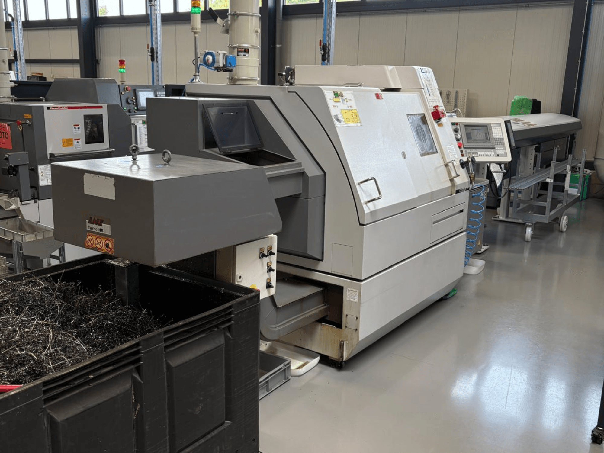 LTA Turbo H8 -teollisuuskone, sivukuva, jossa on suuri säiliö metallilastuille ja ohjauspaneeli tehdasympäristössä.