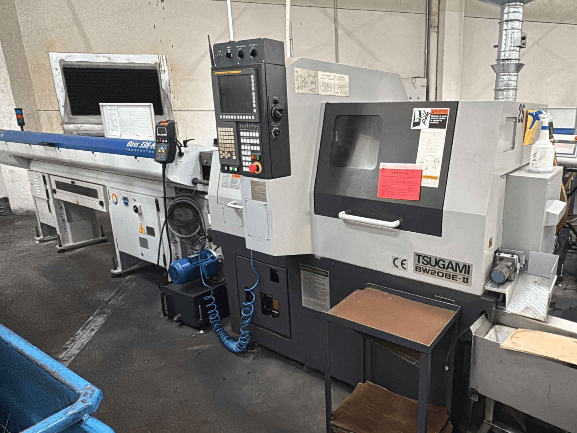 Tsugami BW208E-II CNC-kone työpajassa etukulmasta kuvattuna, ohjauspaneeli ja turvatarrat näkyvissä.