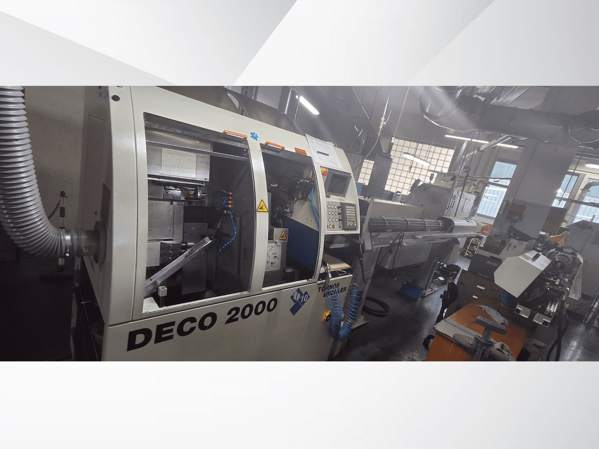 DECO 2000 CNC-kone työpajassa, etukuva, jossa näkyy hallintalaitteet ja oikealla pitkä työkappaleen asetelma.