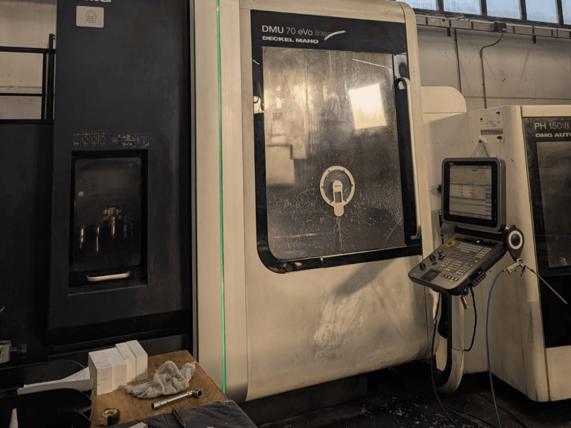 DMG DECKEL MAHO DMU 70 EVO Lineaarinen vertikaalinen työstökeskus, etukuva, jossa ohjauspaneeli, työkalut ja työtila näkyvissä.