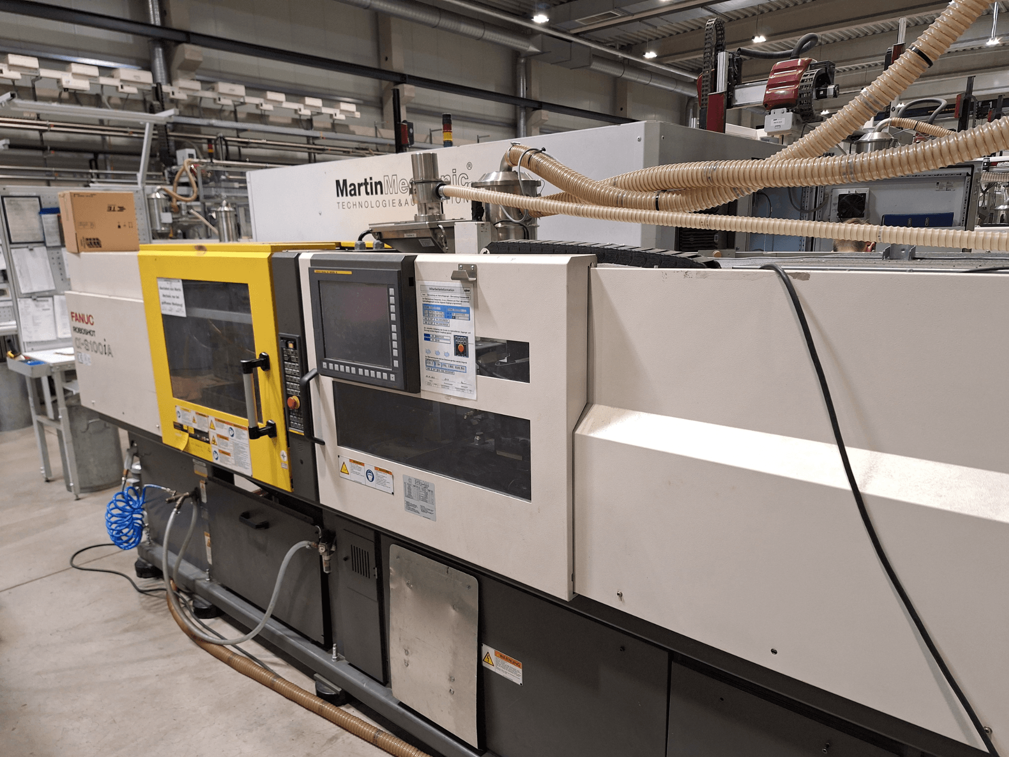 FANUC Roboshot S100iA sähköinen ruiskuvalukone, sivukuva, varustettu kosketusnäytöllä ja turvatarroilla.