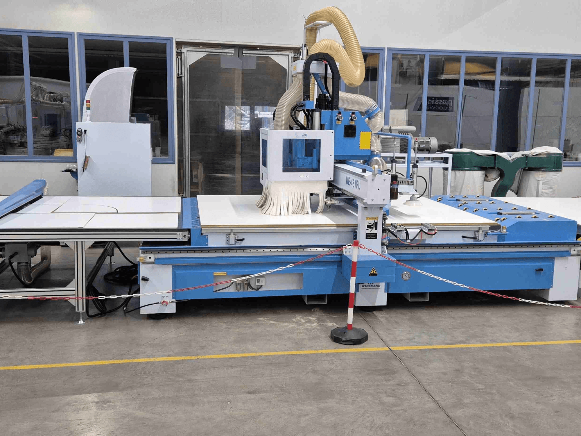 Sininen CNC-jyrsin UE-621PL edestä, jossa on suuri leikkuupöytä ja siihen liitetty pölynpoistojärjestelmä.