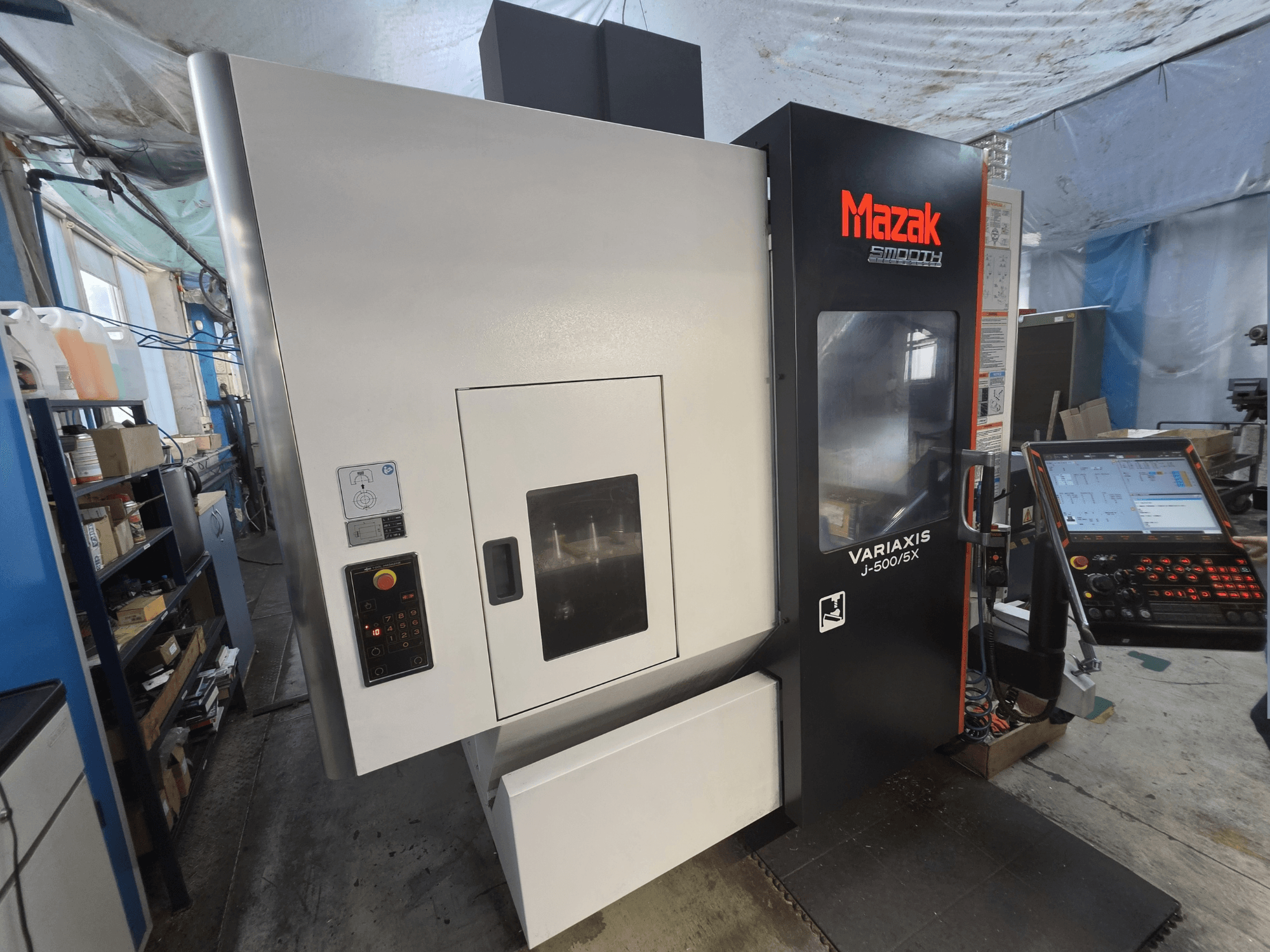 Mazak VARIAXIS J-500/5X -pystykoneistuskeskus edestä katsottuna; kuvassa näkyvät ohjauspaneeli ja suuri koneistusalueen ikkuna.