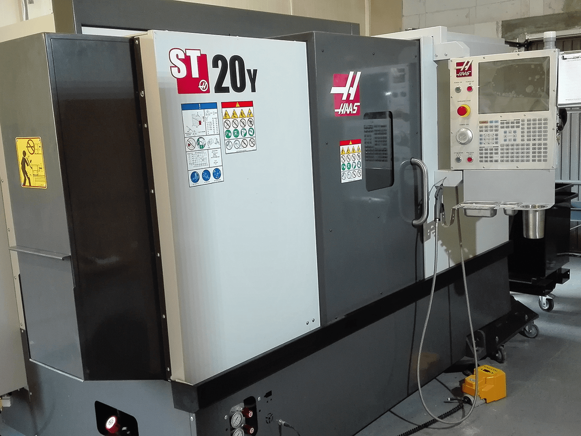 Haas ST20Y CNC-sorvi etukuvassa, jossa on käyttöpaneeli, turvatarrat ja jäähdytysjärjestelmä.