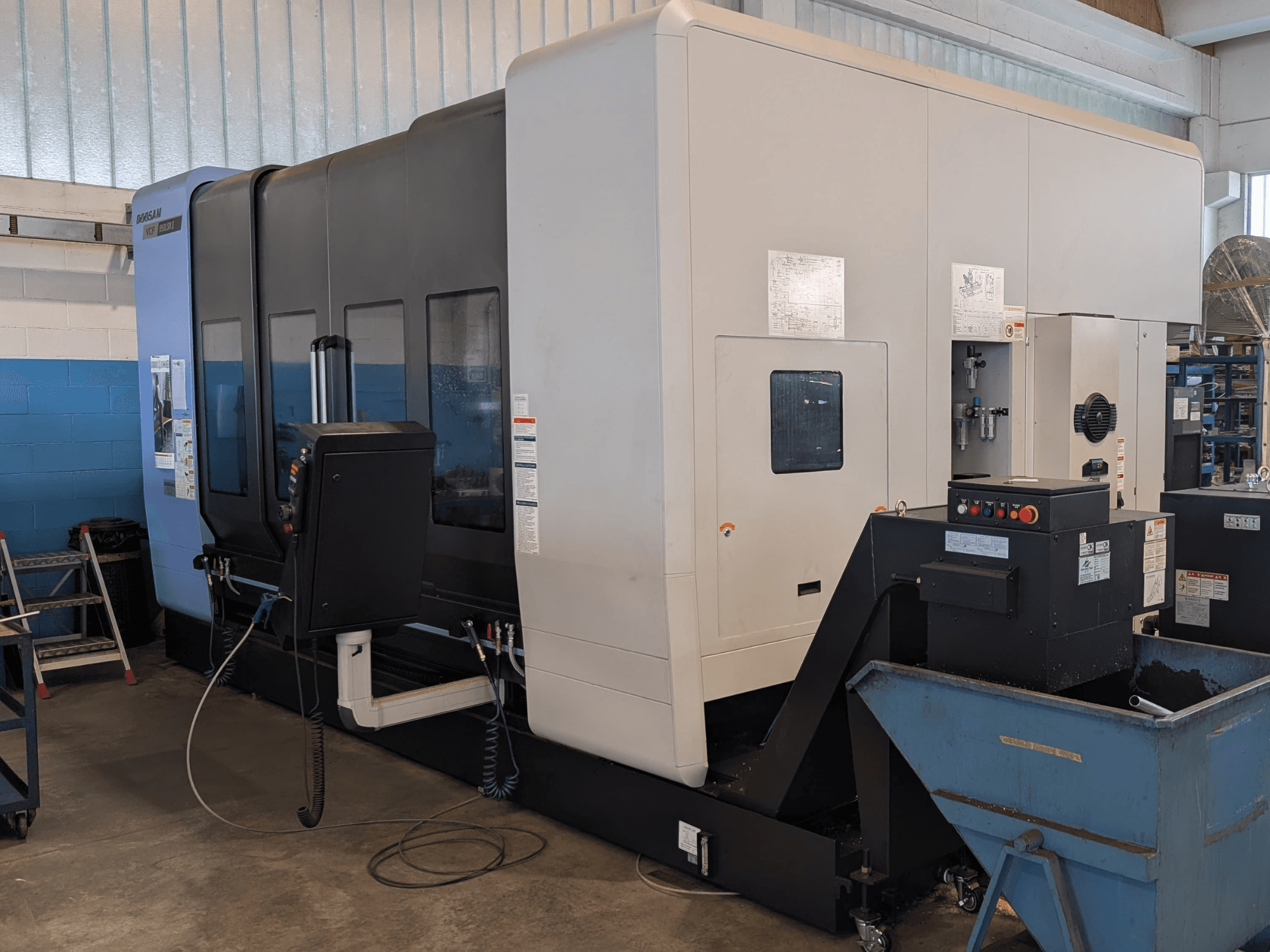 DOOSAN VCF850LSR-II -pystykoneistuskeskus sivulta katsottuna; kuvassa näkyvät ohjauspaneeli, jäähdytysnestejärjestelmä ja vankka rakenne.