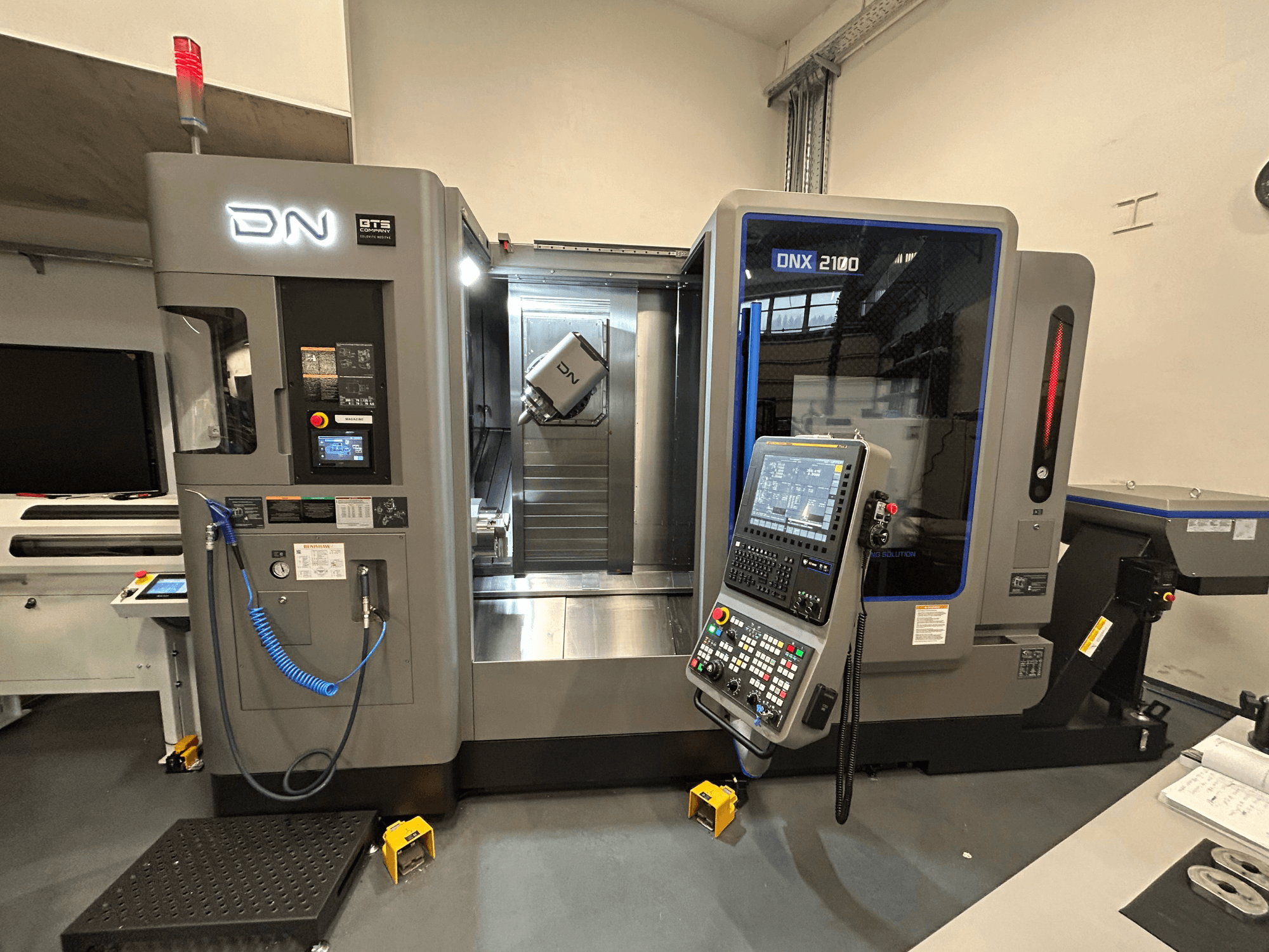 DN ONX 2100 CNC-kone, etukuva, jossa on ohjauspaneeli, työalue ja työkalu. Varustettu turvavalolla ja toiminnan ilmaisimilla.