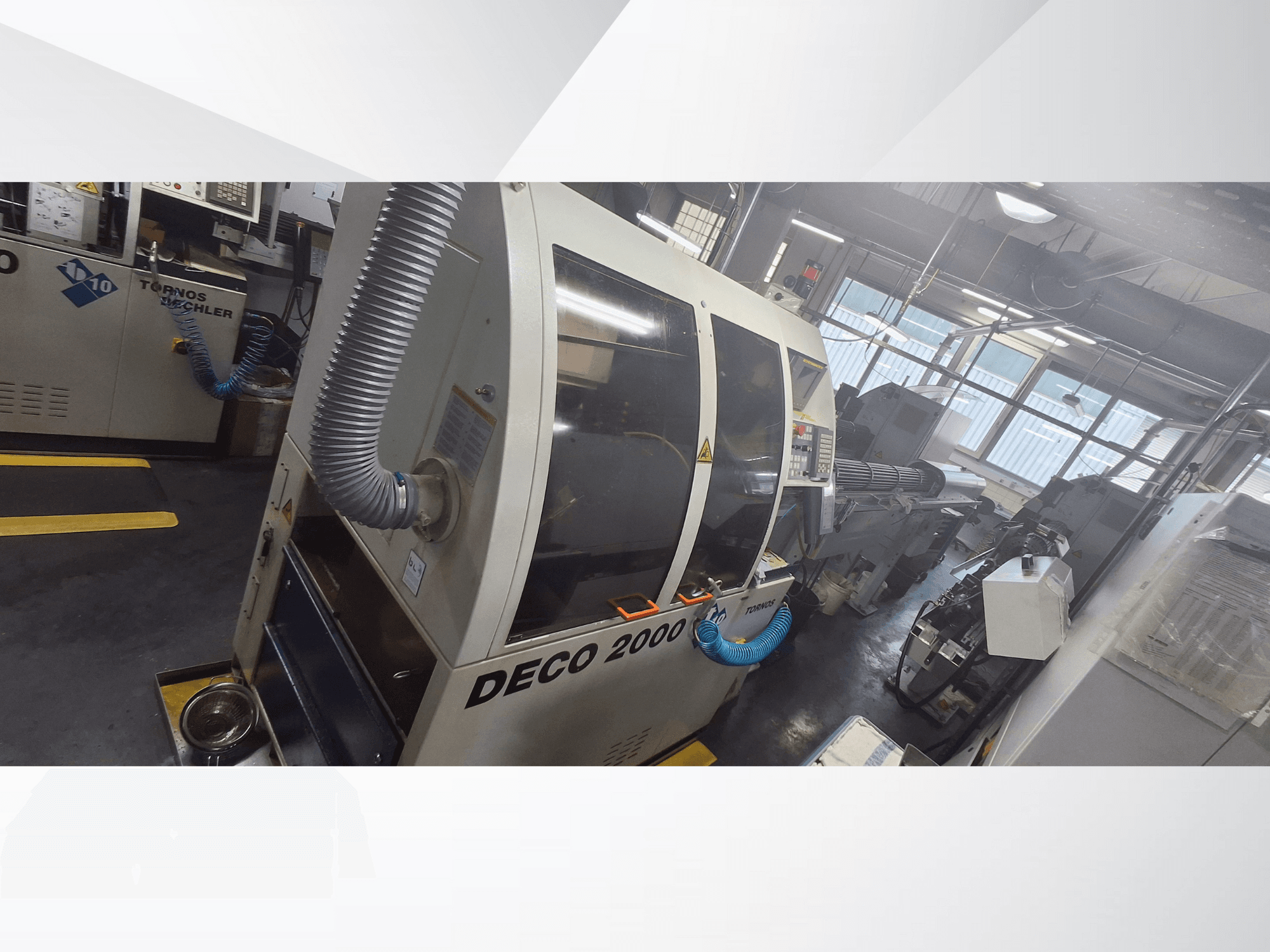 DECO 2000 CNC-kone työpajassa, etukuva, jossa on tuuletusletku ja ohjauspaneeli, suunniteltu tarkkuustyöstöön.