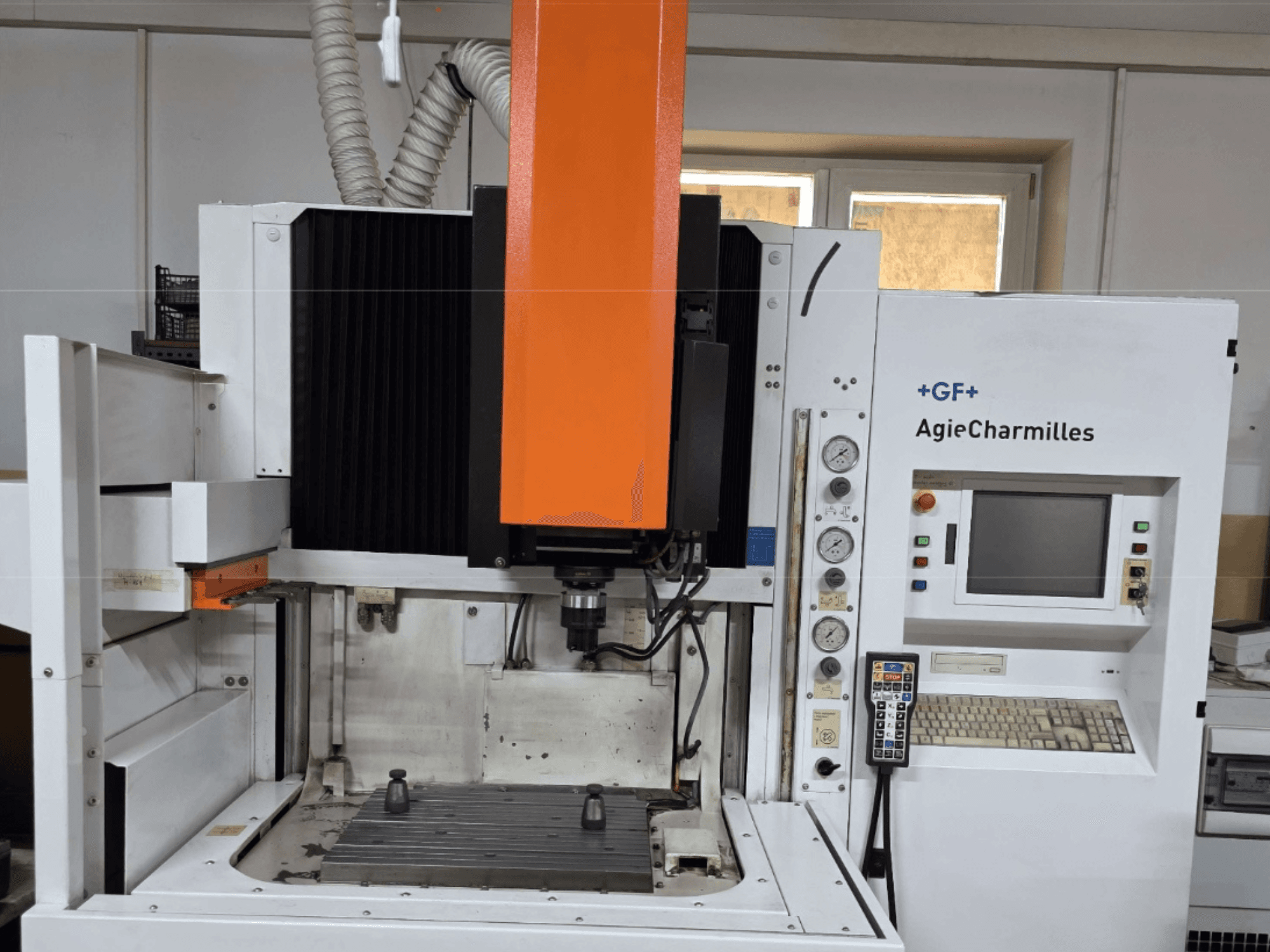 AgieCharmilles-työstökeskus etukuvassa, jossa on suuri oranssi kara, ohjauspaneeli ja näkyvä työpöytä.