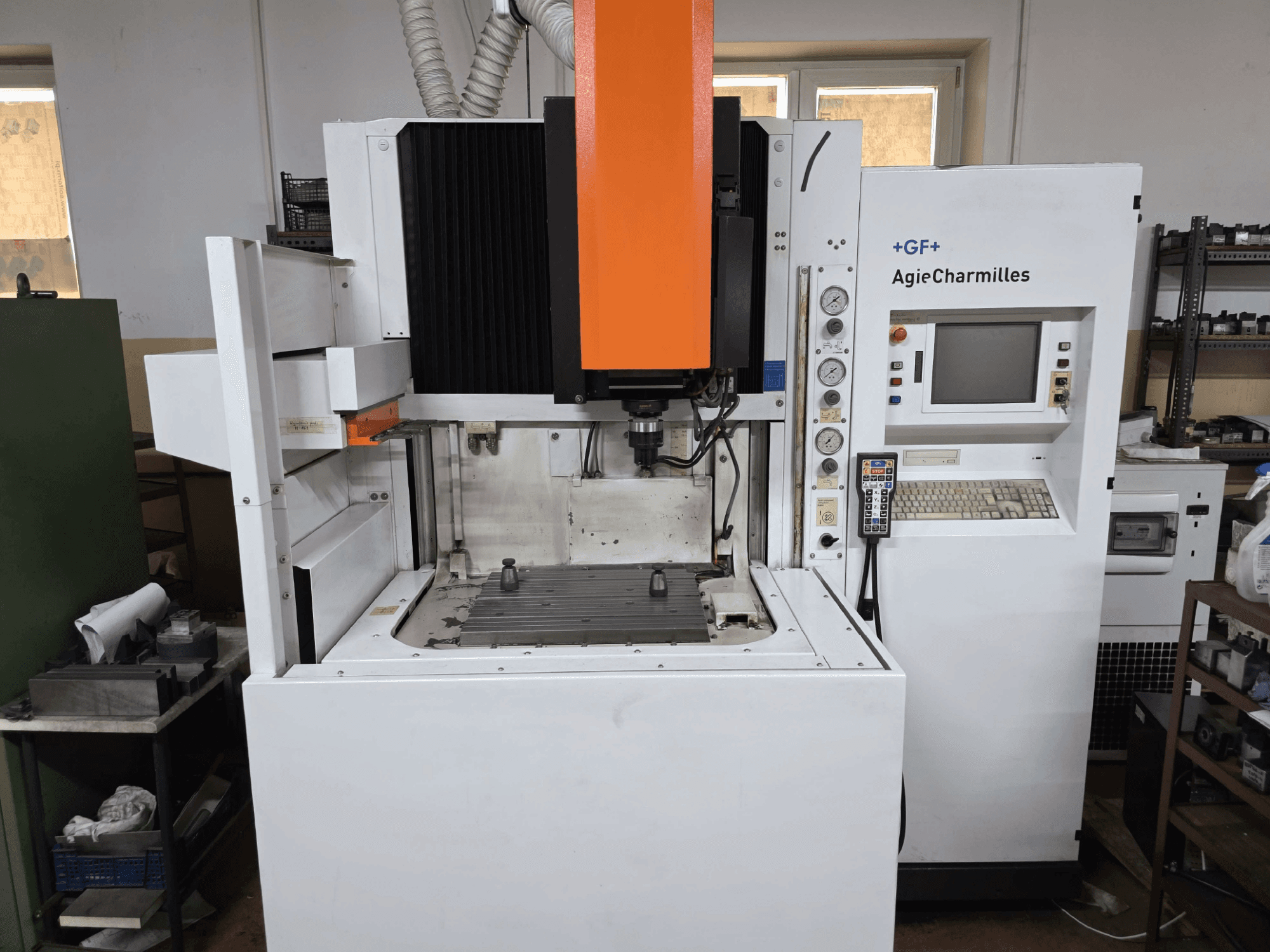 GF AgieCharmilles CNC-kone, etukuva, jossa on näkyvä oranssi kara, digitaalinen ohjauspaneeli ja asennettu porauspöytä.