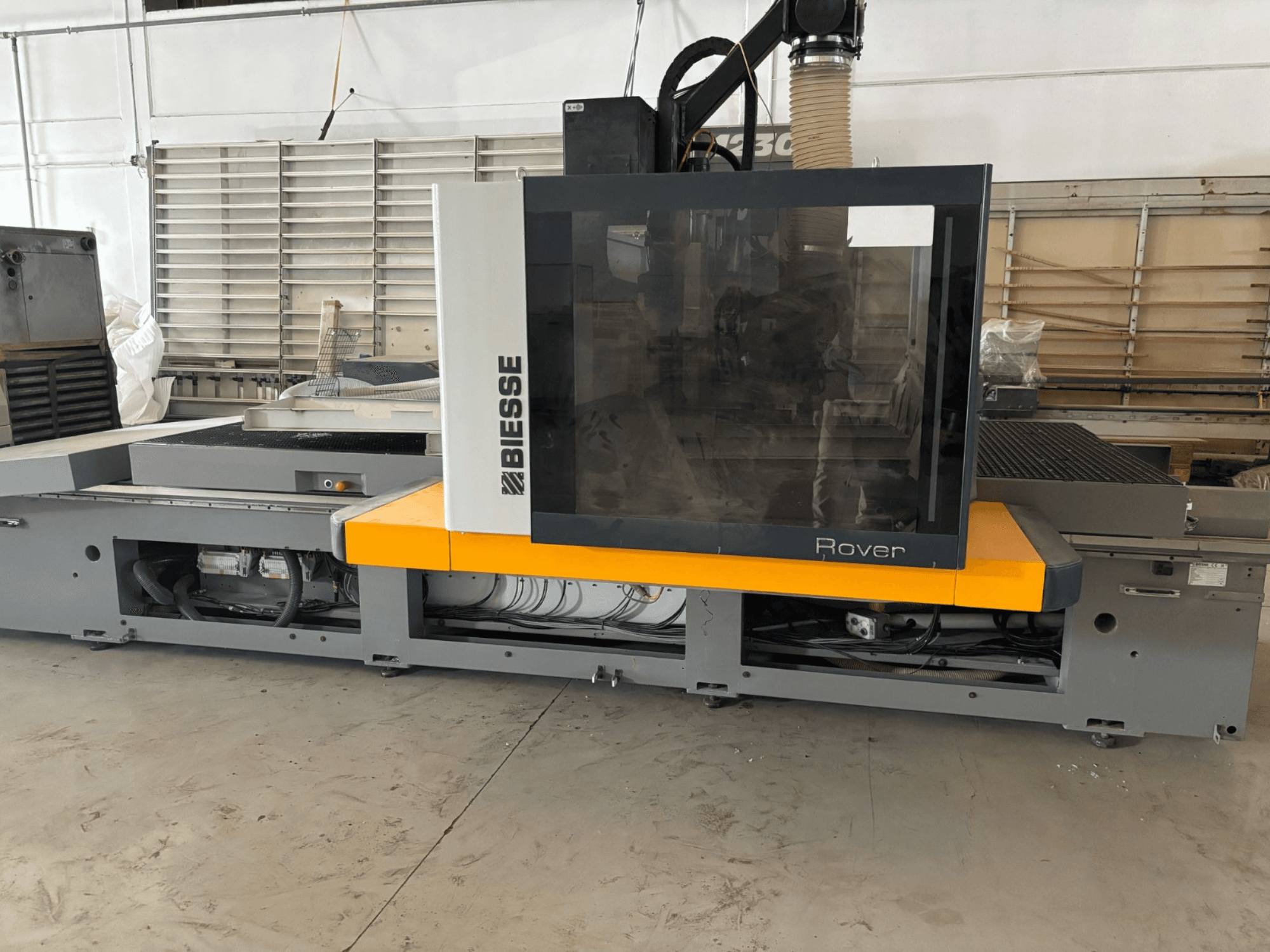 Biesse Rover CNC-työstökeskuksen etukuva, jossa on suuri ohjauspaneeli, keltaiset korostukset ja näkyvillä olevat mekaaniset osat.