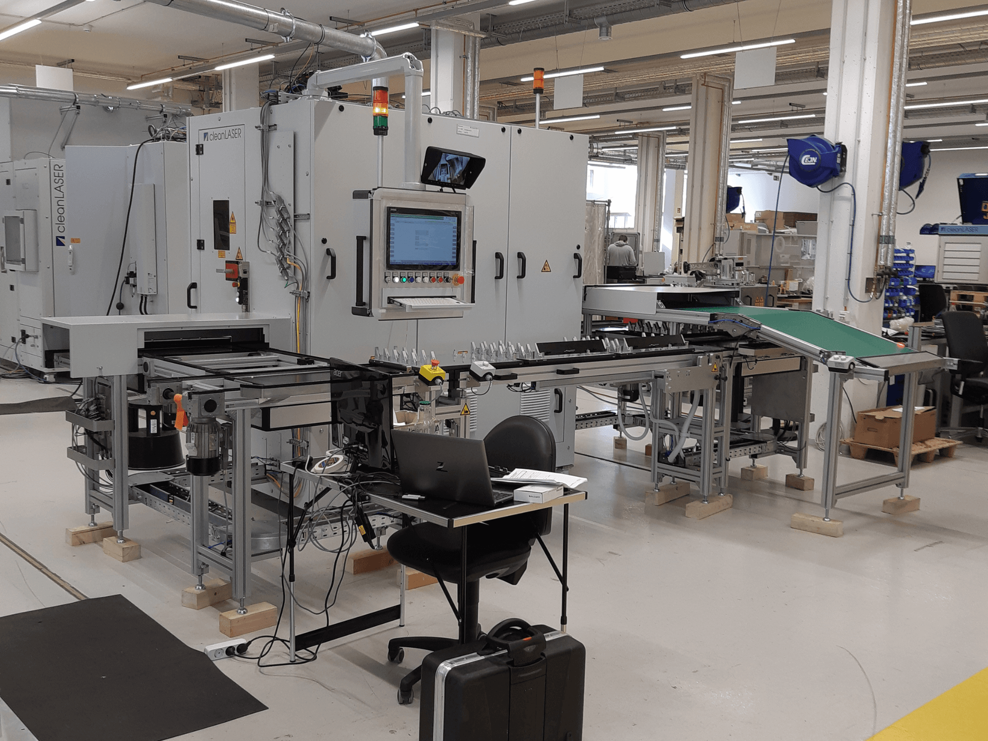CLEAN LASER clean CELL 3220 -työstökone, etunäkymä, jossa näkyvät ohjauspaneeli, kuljetin ja työtilan järjestely tehdasympäristössä.