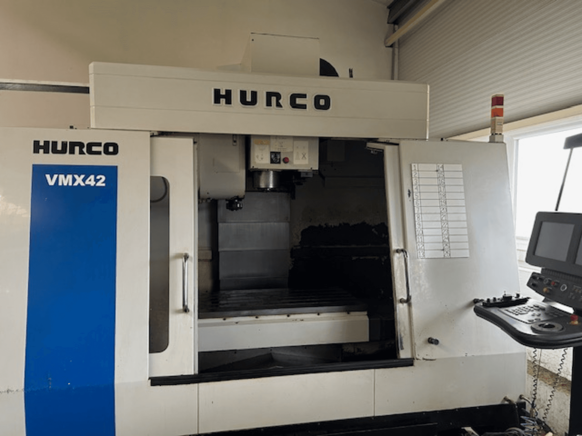 Hurco VMX42 CNC-kone etukuvassa, jossa näkyy ohjauspaneeli, kara ja työskentelyalue; paljastaa toiminnallisen ulkoasun.