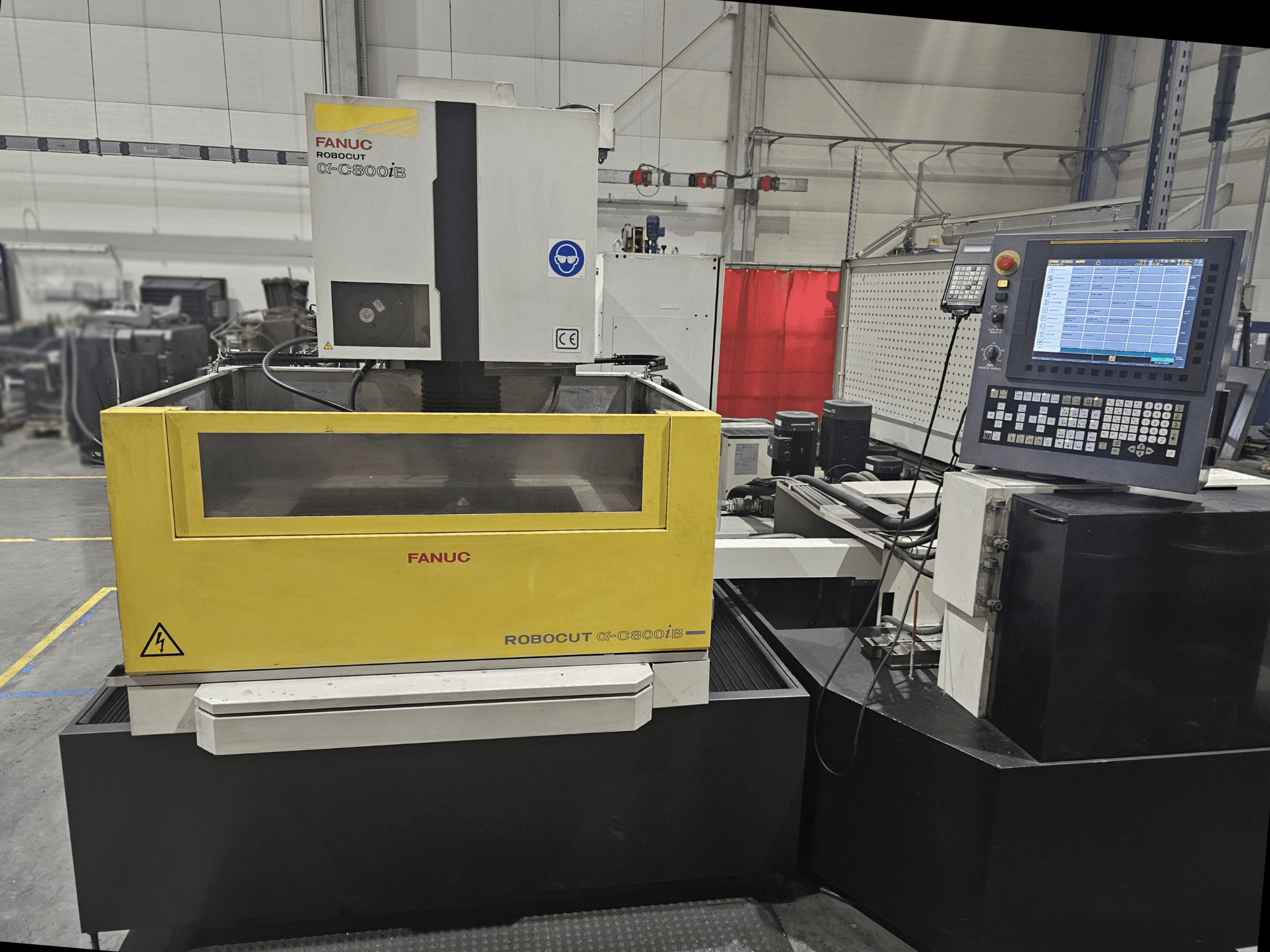 FANUC Robocut α-C600iB:n etukuva, jossa on keltainen ja harmaa koneen runko, CNC-ohjauspaneeli ja toimintanäyttö.