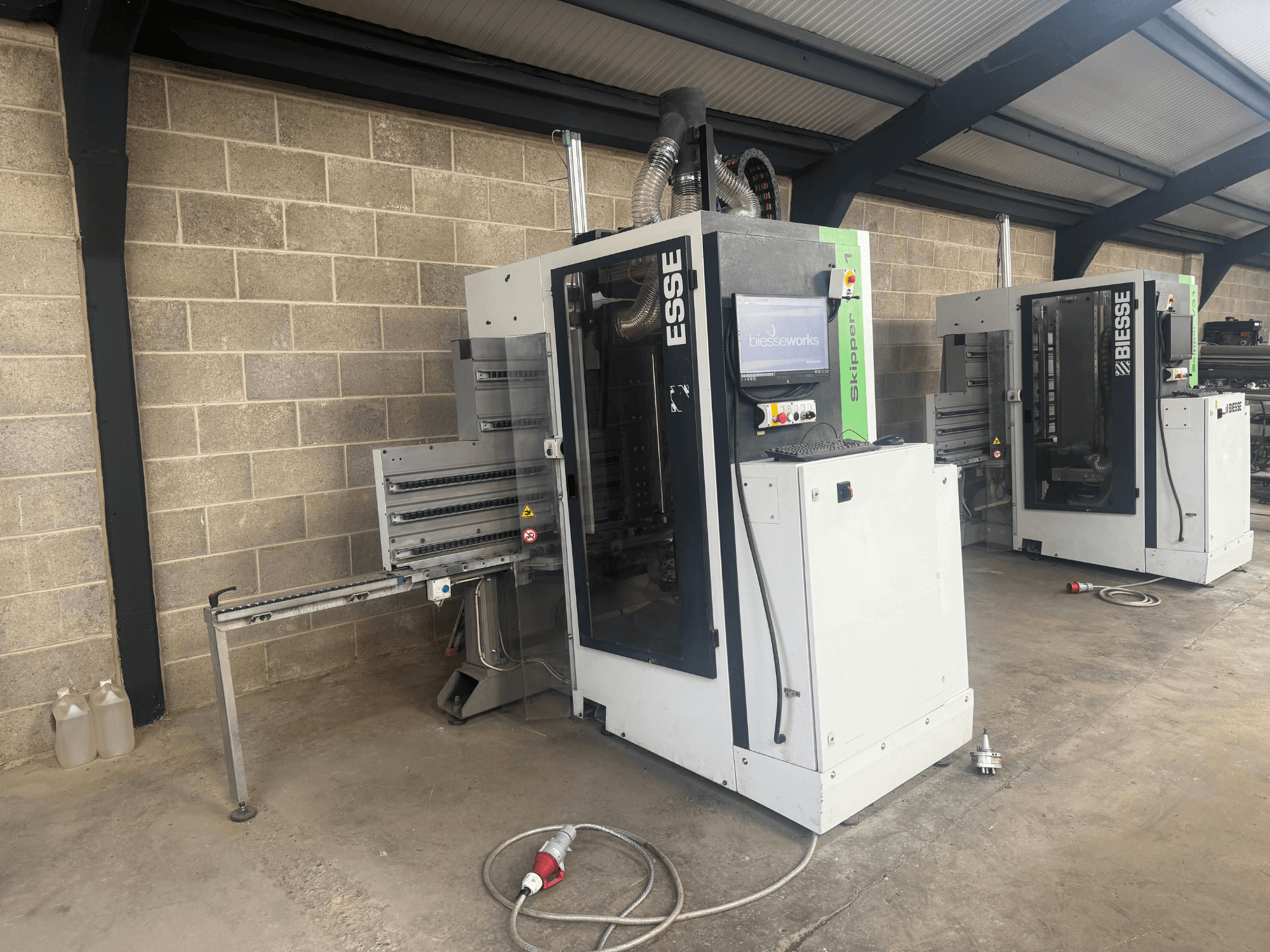 BIESSE Skipper v31 puunporauskone sivukuvassa, jossa ohjauspaneeli ja viereiset koneet, työpajassa.