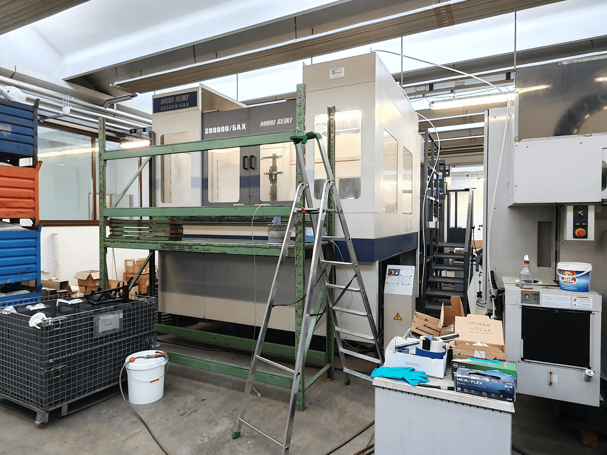 Mori Seiki SH-8000/5AX CNC-kone työpajassa, etukuva, työpajan työkalut ja säilytyslaatikot vieressä.