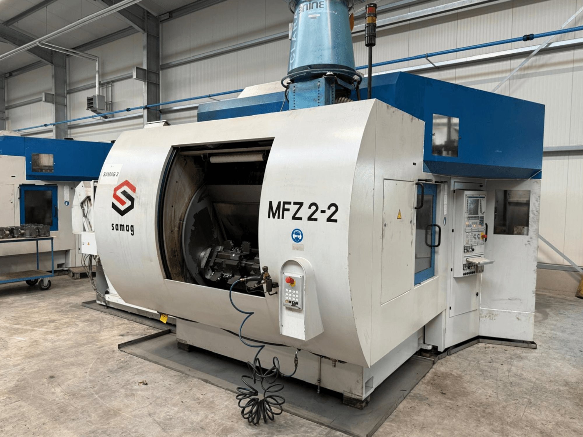 Samag MFZ 2-2 -jyrsinkone sivukuvassa, jossa näkyy suuri, avoin kammio ja ohjauspaneeli, jossa on erilaisia painikkeita ja säätimiä.