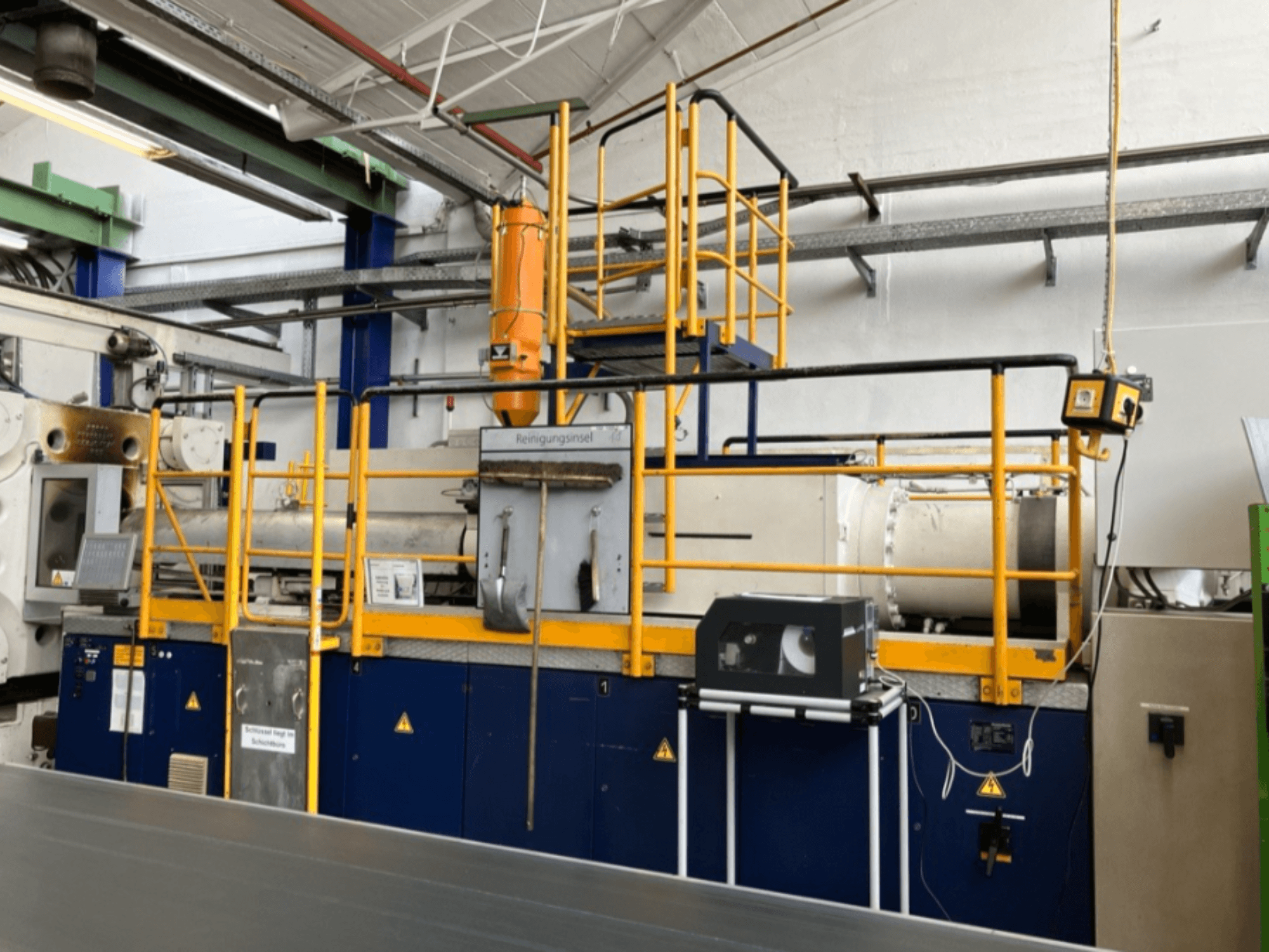 Krauss Maffei 1000-8000 M hydraulinen ruiskuvalukone, sivukuva, jossa turvakaide ja ohjauspaneeli näkyvissä.