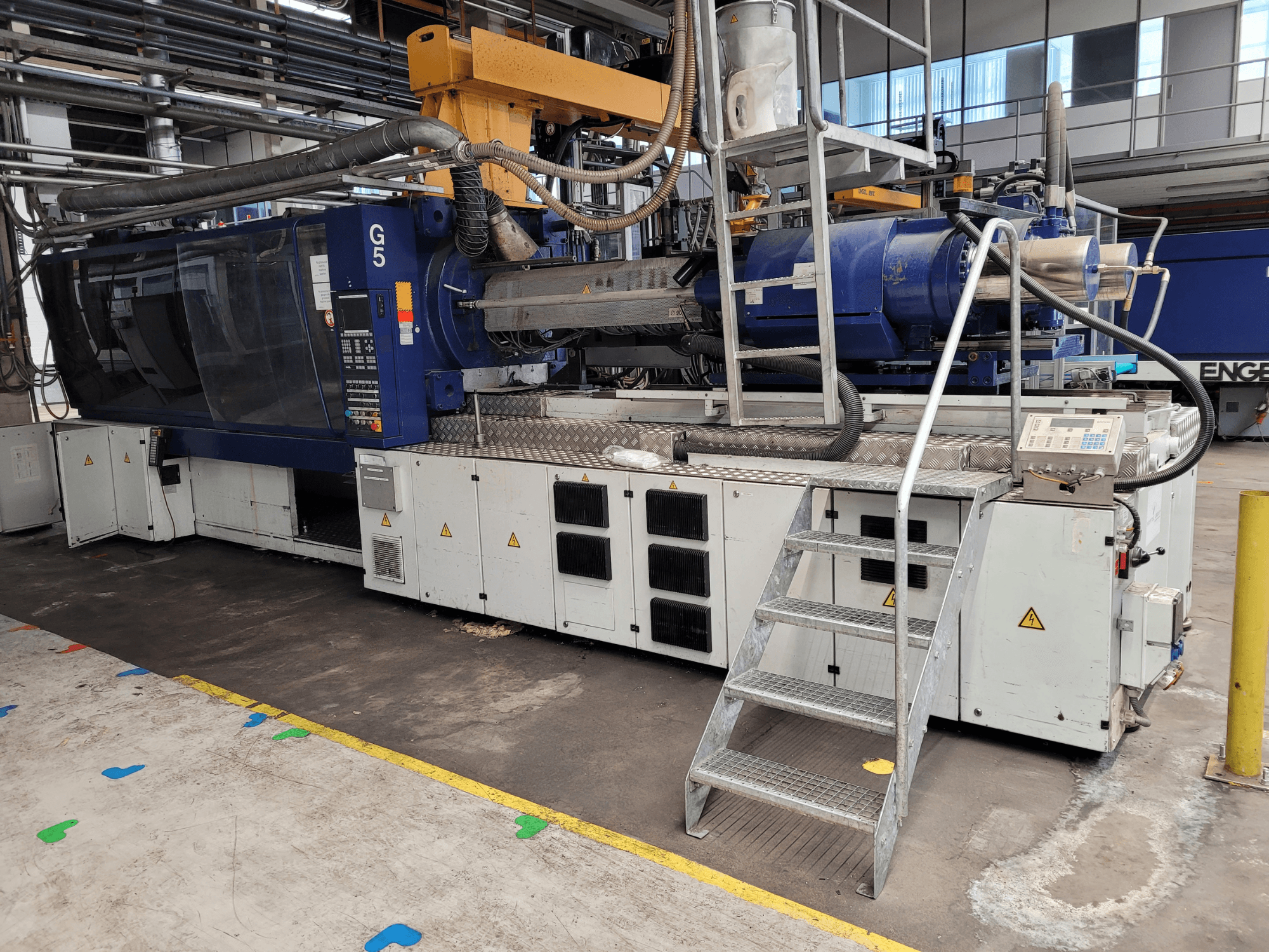 Ruiskuvalukone G5, sivukuva, jossa ohjauspaneeli, porrastikkaat ja ruostumattomasta teräksestä valmistettu työtaso näkyvissä.