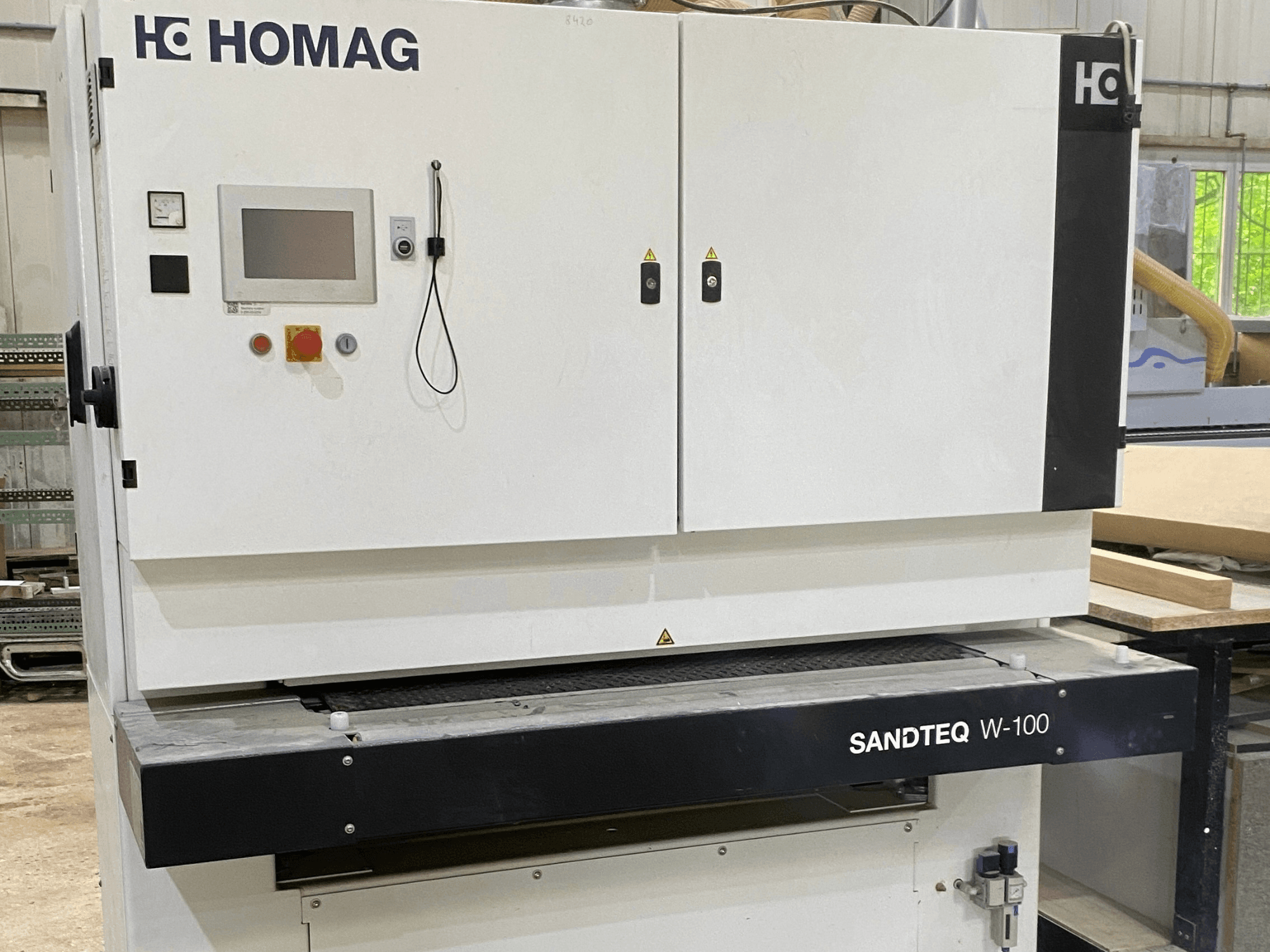 HOMAG SANDTEQ W-100 -hihnahiomakone työpajassa; kuvassa näkyvät ohjauspaneeli, pölynpoistoliitäntä ja hiomanauha-alue. Etunäkymä.