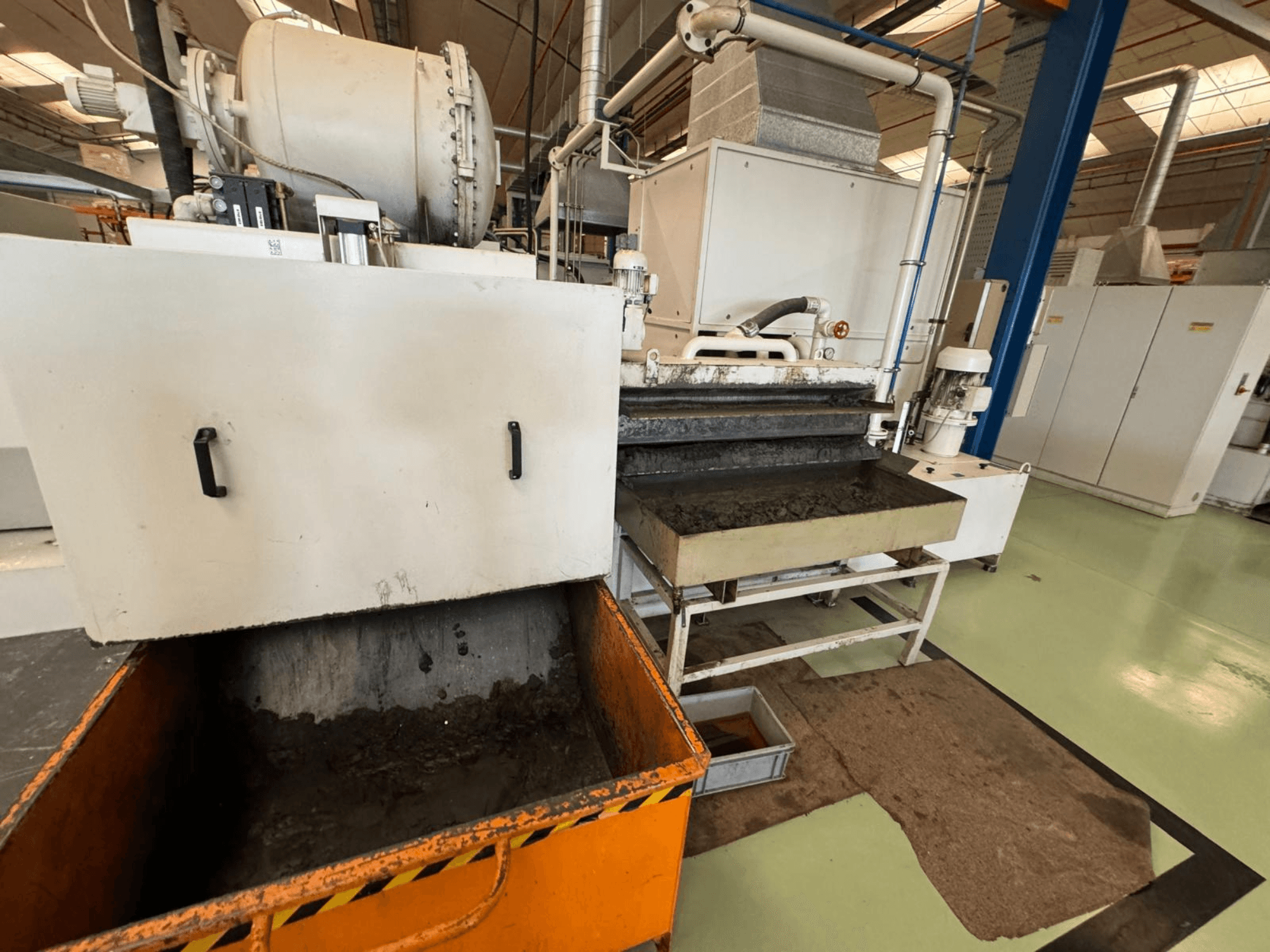 Teollisuuden käsittelylaitteisto, jossa on oranssi jäteastia, etukuva; sisältää moottorin, kuljettimet ja huoltotilan.