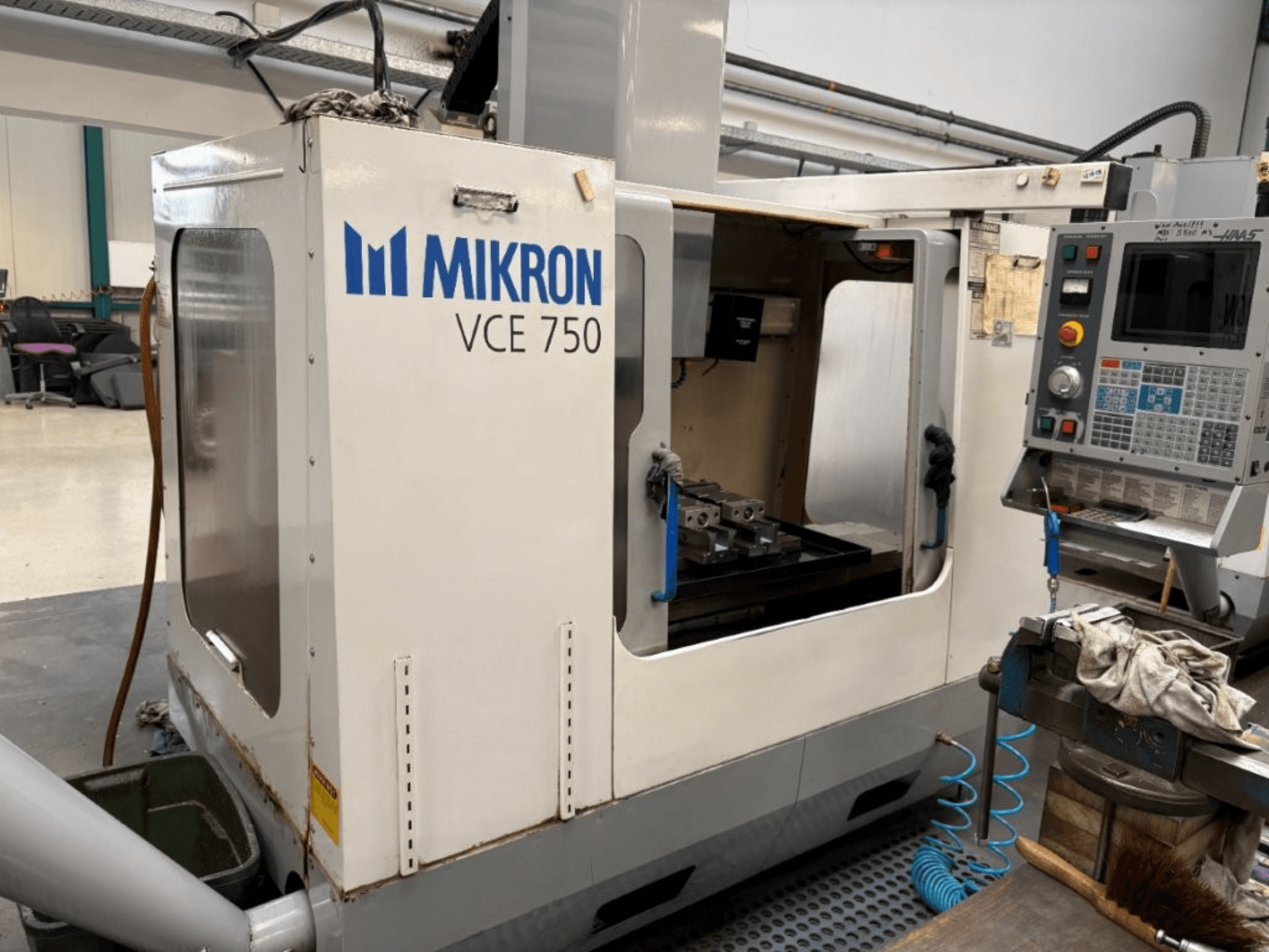 Mikron VCE 750 CNC-jyrsinkoneen etukuva, jossa on työstetty työpöytä ja ohjauspaneeli, jossa on erilaisia painikkeita ja näyttöjä.