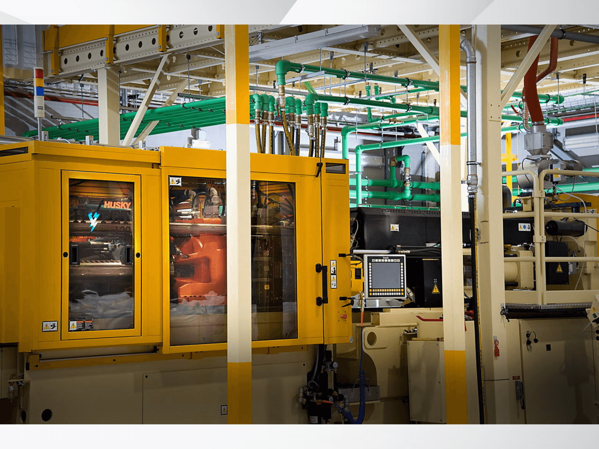 Keltainen Husky-teollisuuskone, etukuva, jossa näkyy ohjauspaneeli ja sisäiset mekanismit tehtaan taustaa vasten.