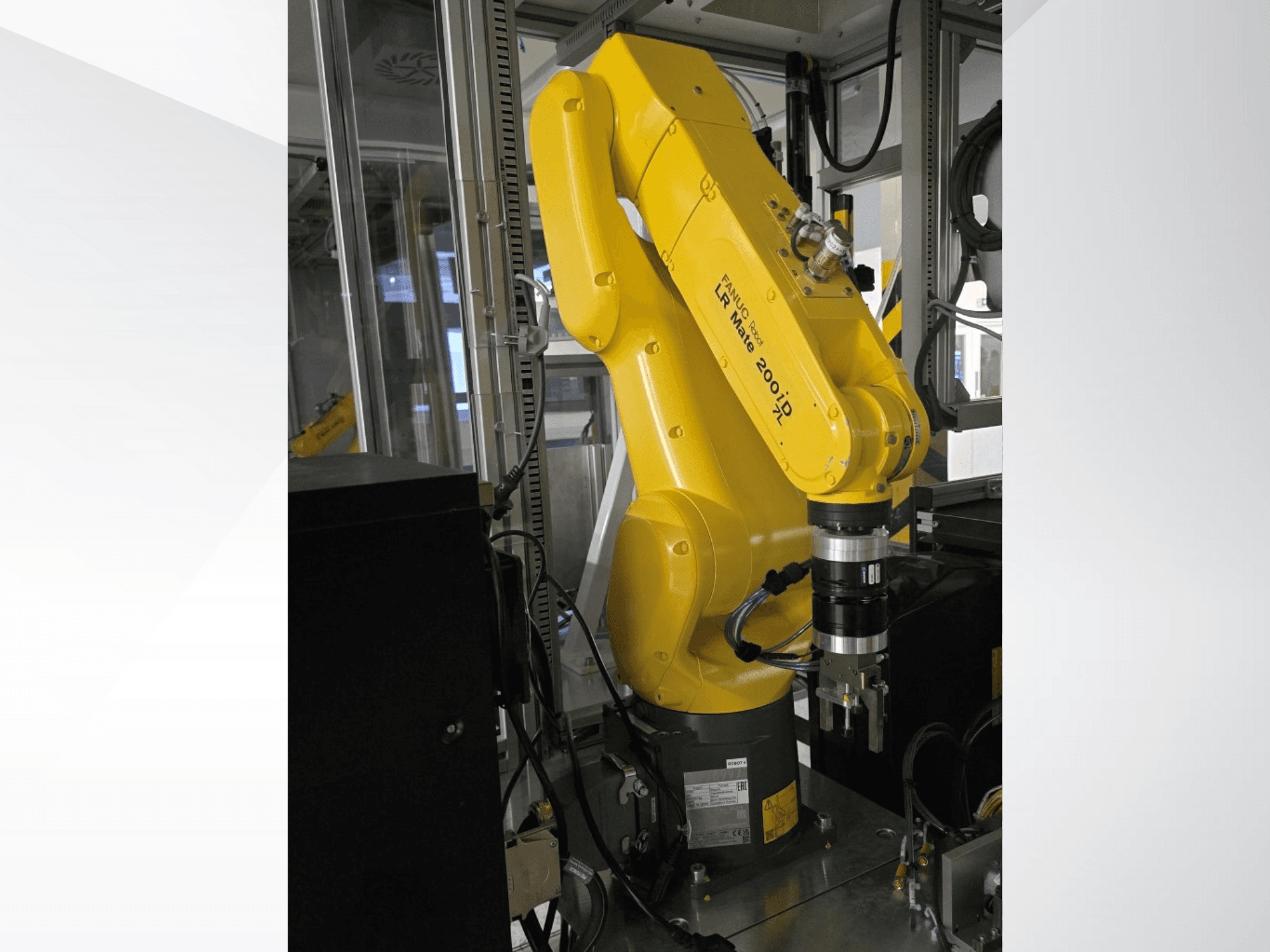 Keltainen Fanuc LR Mate 200iD -robottikäsivarsi sivukuvassa, jossa on tarttuja ja erilaisia kaapeleita kiinnitettynä.