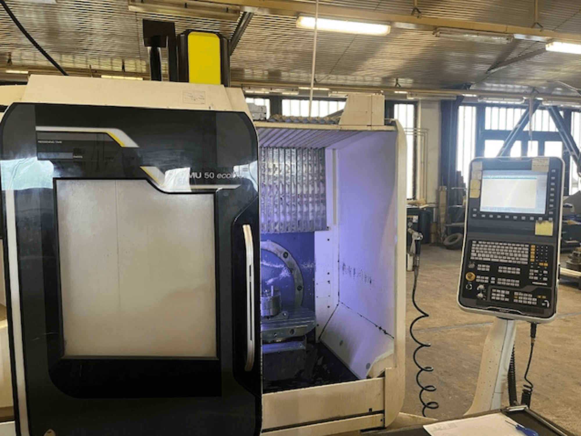 DMU 50 eco -jyrsinkoneen etukuva ohjauspaneelista, jossa näkyy työkalunpidin ja työtila.