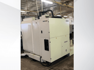 Valkoinen teollinen CNC-kone edestä katsottuna, jossa on ohjauspaneeli ja ilmanvaihto, työpajan ympäristössä.