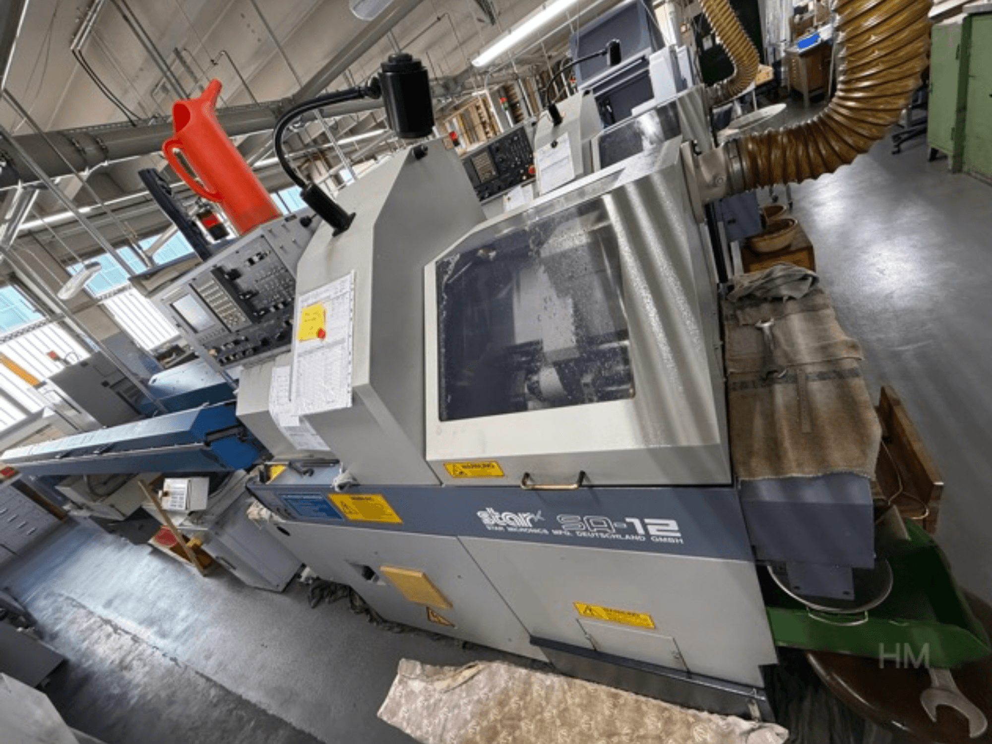 Star SQ-12 -työstökeskus, sivukuva, jossa ohjauspaneeli, jäähdytysnestesäiliö ja pölynpoistoletku näkyvissä.