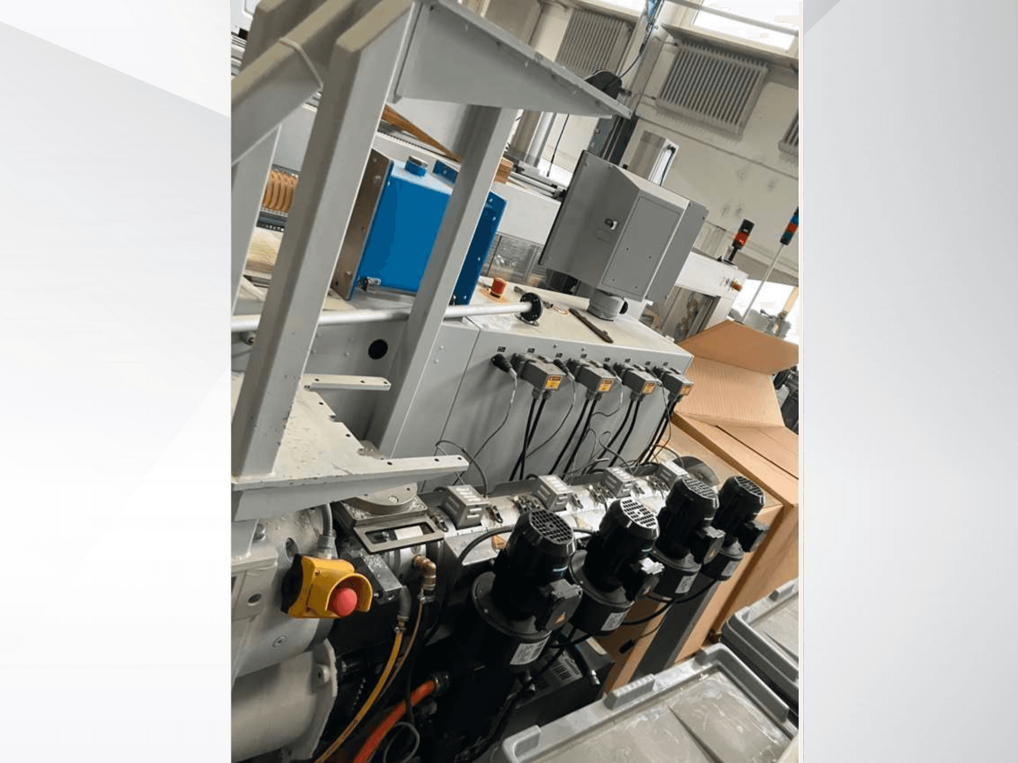 Teollisuuskoneiden ohjauspaneeli, jossa on useita moottoreita, mittareita ja monitori; sivukuva tehdasympäristöstä.