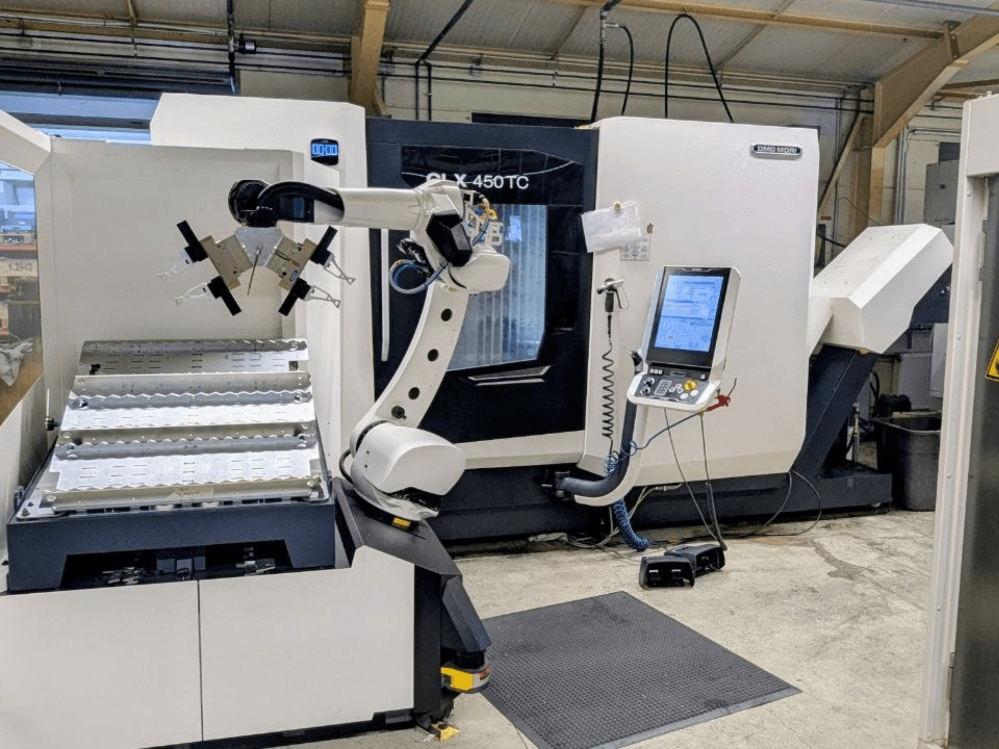 DMG MORI CLX 450 TC ja Robo2go, etunäkymä, jossa näkyy robottivarsi ja koneen vieressä oleva ohjauspaneeli.
