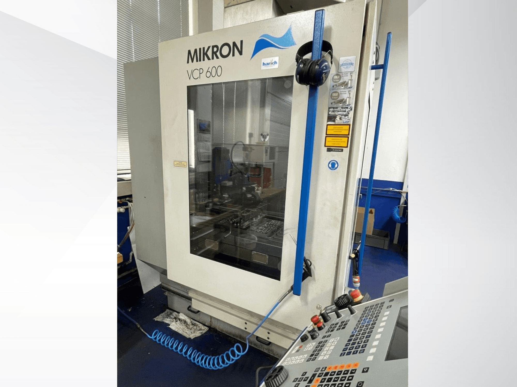 Mikron VCP 600 CNC-kone, etukuva, jossa on ohjauspaneeli painikkeineen ja näkyvissä oleva työstöalue lasin takana.