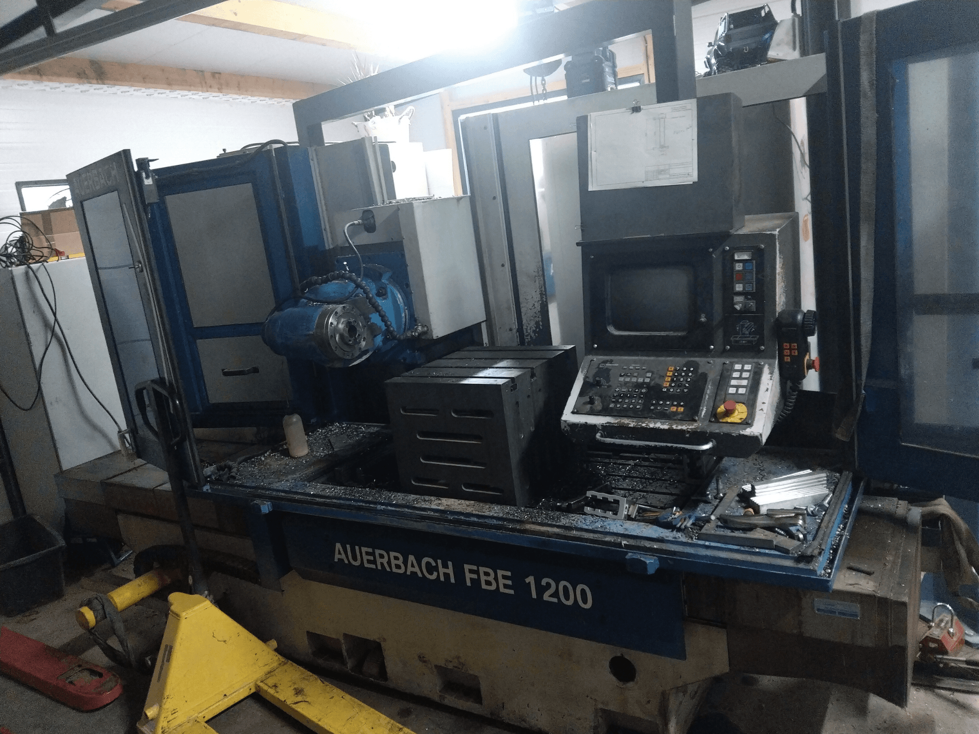 Auerbach FBE 1200 -metalliporakone, etukuva, jossa näkyy ohjauspaneeli, moottori ja metallilastuja työpinnalla.