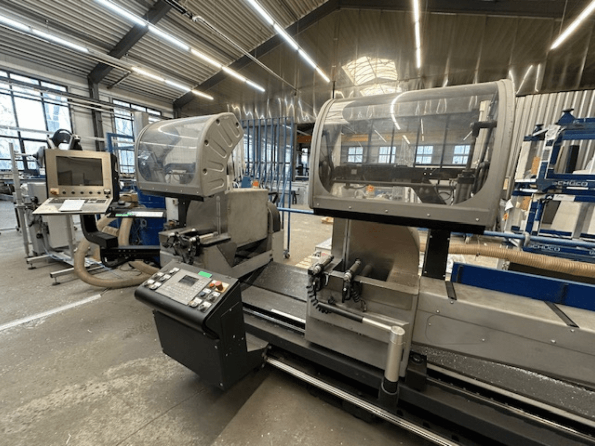 SCHÜCO PDG E CUT -metallipyörösaha, etukuva, jossa on ohjauspaneeli, suojakannet ja leikkausalue työpajatilassa.