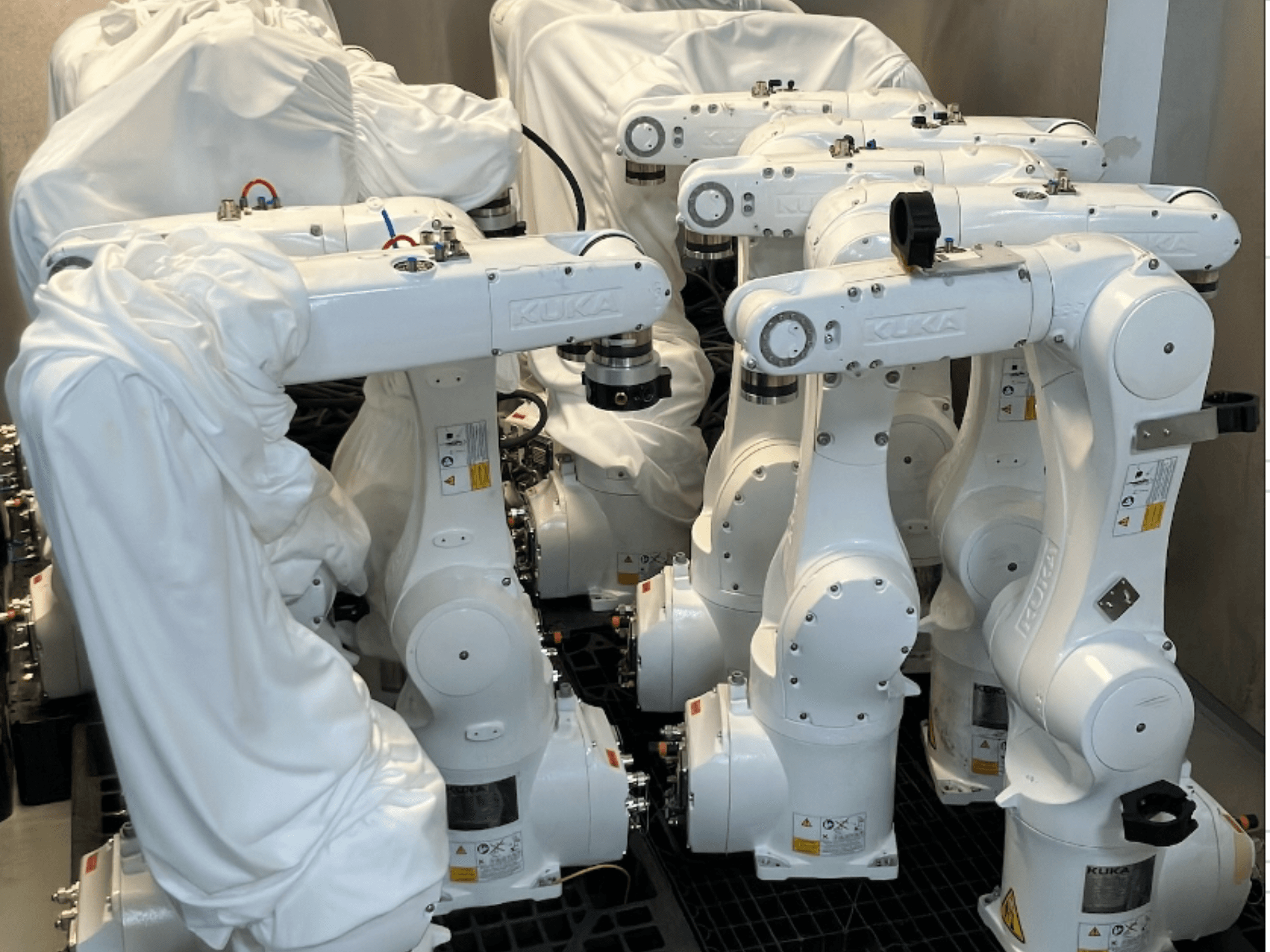 KUKA KR 10 R900-2 -robottivarret osittain kankaalla päällystettyinä, edestä katsottuna, jolloin niiden tyylikäs valkoinen muotoilu ja tekniset yksityiskohdat tulevat esiin.