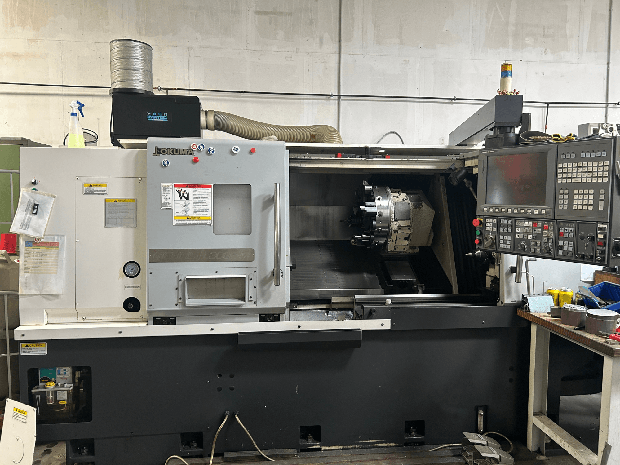 Etukuva Okuma Genos L300E-M -vaakasorvauskoneesta, jossa on ohjauspaneeli, näkyvä kara ja erilaisia asetustyökaluja.