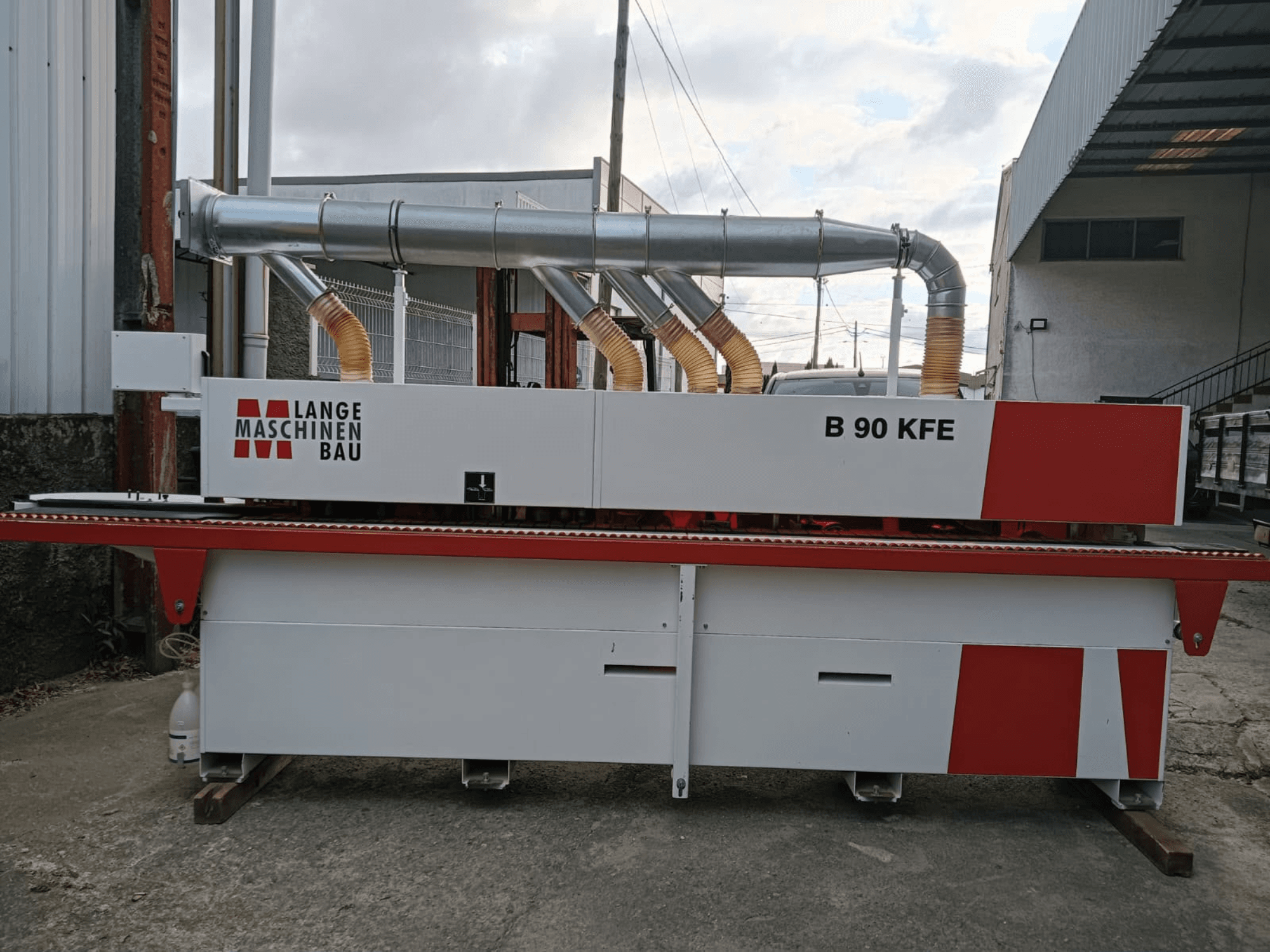 LANGE Maschinenbau B 90 KFE -reunakone sivulta katsottuna, varustettuna kahdella pakoputkella ja punaisilla yksityiskohdilla, sijoitettuna teolliseen työtilaan.