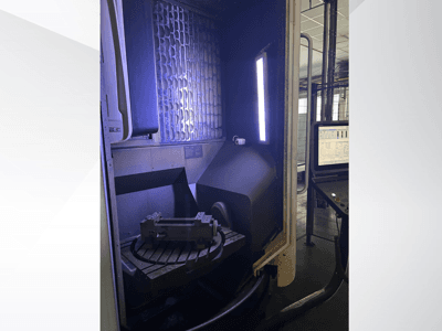 DMG MORI DMU 65 MonoBlock -pystykoneistuskeskus, etunäkymä, jossa näkyy pyörivä pöytä työkappaleen kanssa sekä ohjauspaneeli.