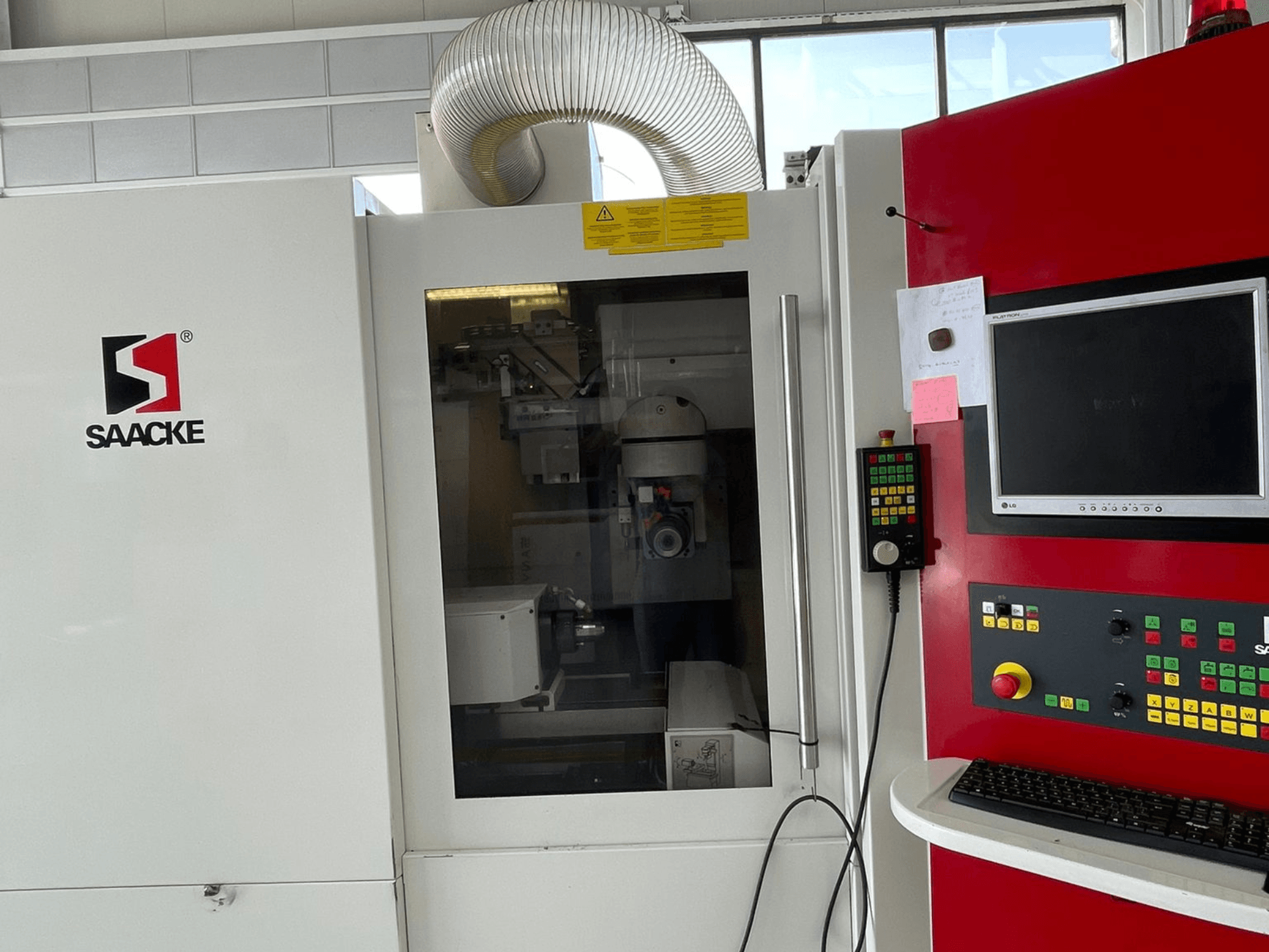 Valkoinen ja punainen SAACKE-kone, etukuva, jossa on ohjauspaneeli, näyttö ja lasin läpi näkyvät sisäosat.