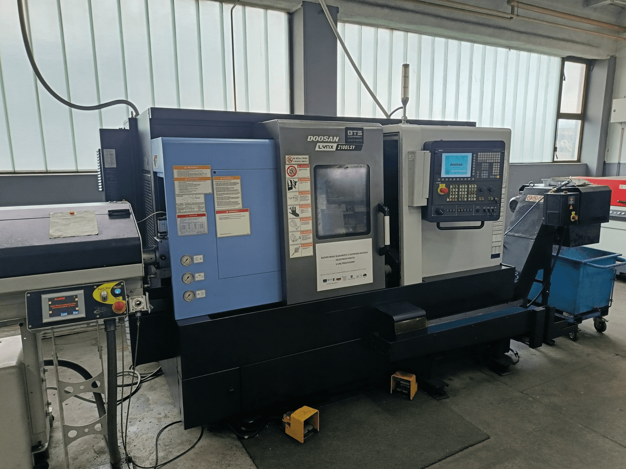 DOOSAN LYNX 2100 LSY -kääntökeskus, sivukuva, jossa näkyy ohjauspaneeli ja käyttöpainikkeet, joissa on näkyvissä merkinnät.