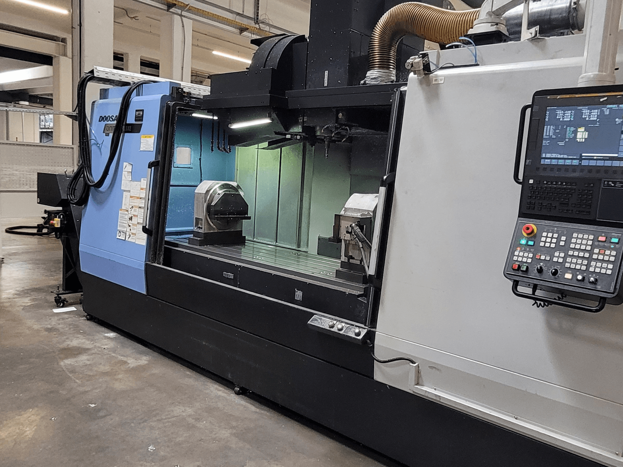 DOOSAN DNM 6700 XL -pystykoneistuskeskus, etunäkymä, jossa näkyvät ohjauspaneeli, työpöytä ja koneistusalue.